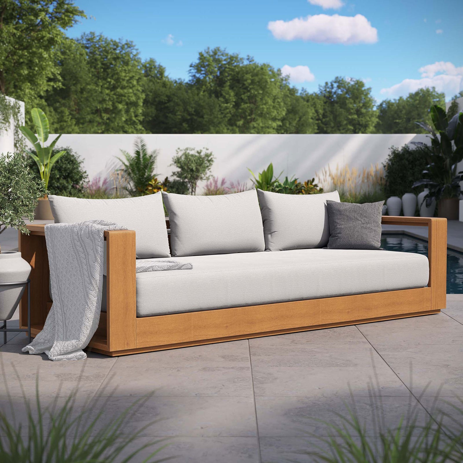 Tahoe outdoor sofa with light gray cushions styled with pillow and throw in a modern patio setting. || EEI-6784-NAT-LGR || front_angle_room