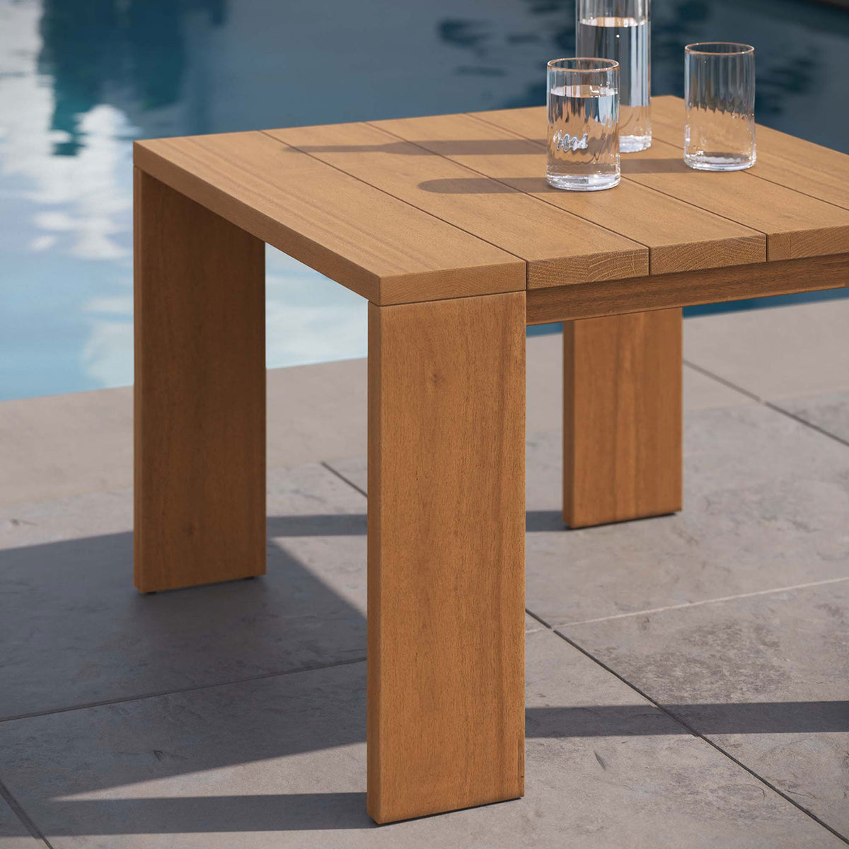 Natural wood side table beside a pool, perfect for holding refreshing drinks and outdoor essentials. || EEI-6787-NAT || front_angle_room