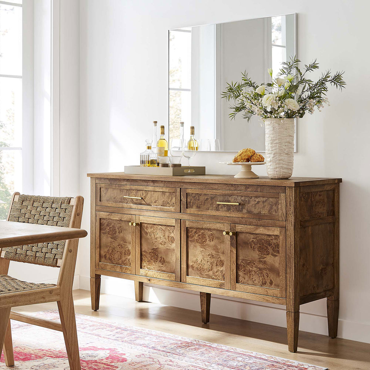 Burl wood sideboard styled in a modern dining room with mirror, flowers, and seating for a welcoming look. || EEI-6794-BRN || front_angle_room