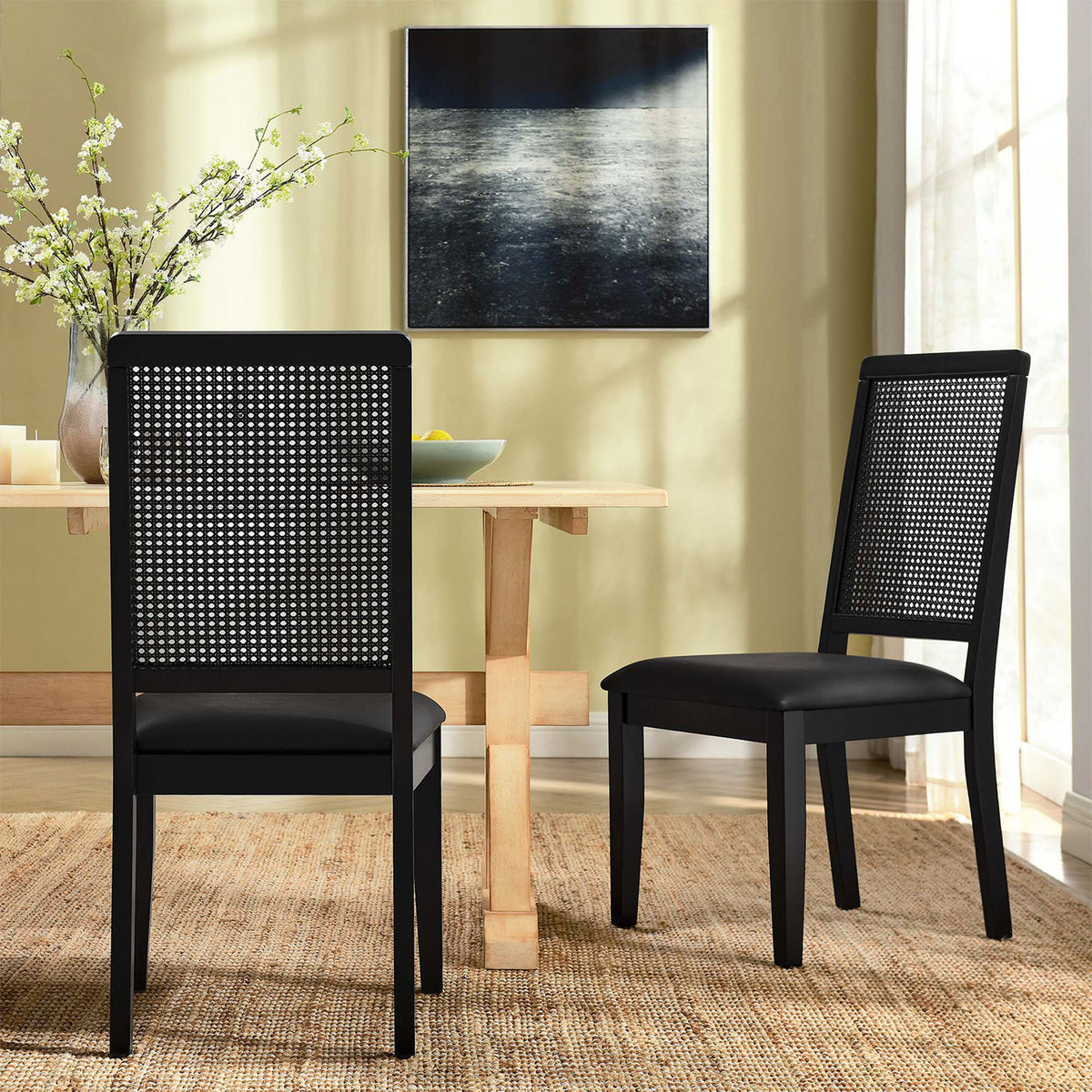 Pair of black vegan leather dining chairs around a light wood table in a cozy modern dining room || EEI-6802-BLK-BLK-BLK || back_angle_multi_room