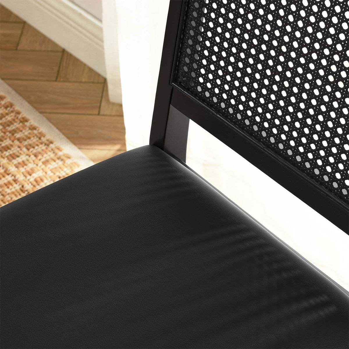 Black vegan leather seat and cane backrest bringing modern contrast to a warm dining room setting || EEI-6802-BLK-BLK-BLK || detail_room