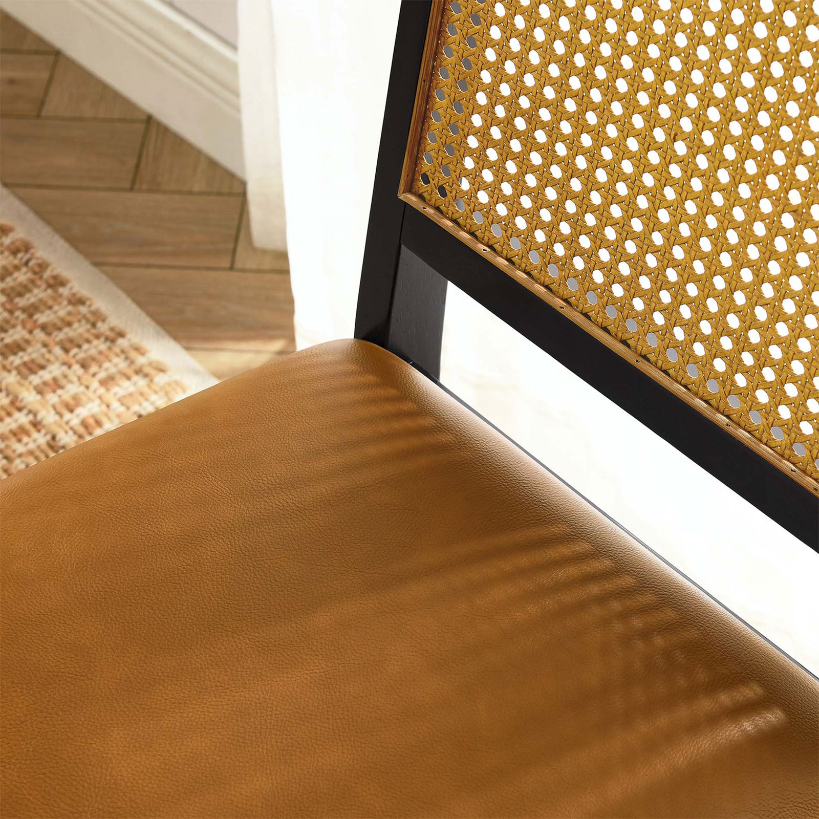 Tan vegan leather seat and woven cane back of dining chair styled beside a sunny window || EEI-6802-BLK-NAT-TAN || detail_room