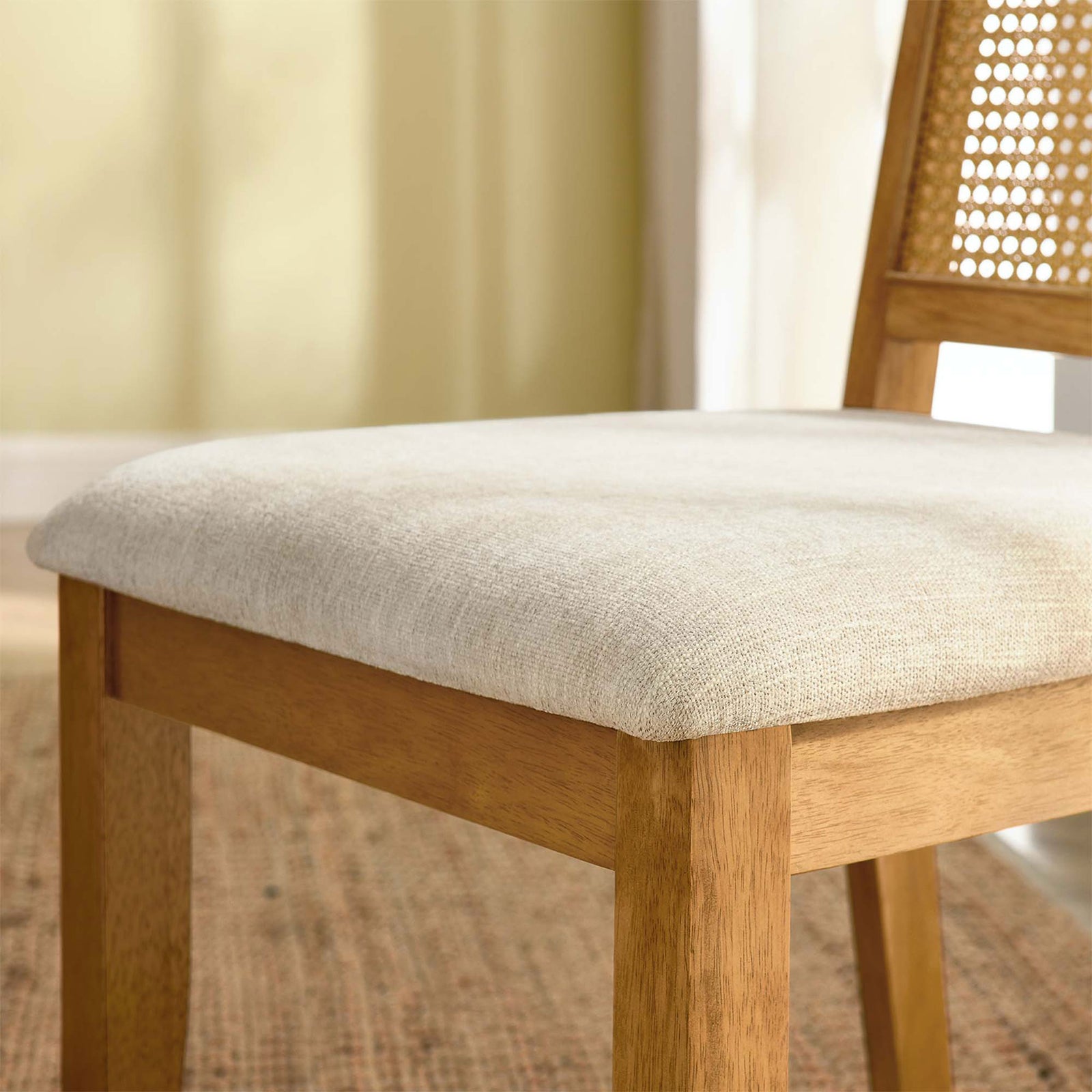 Detail of the Arlo chair cushioned beige fabric seat and warm wood frame over a woven rug || EEI-6803-NAT-NAT-HLB || detail_room