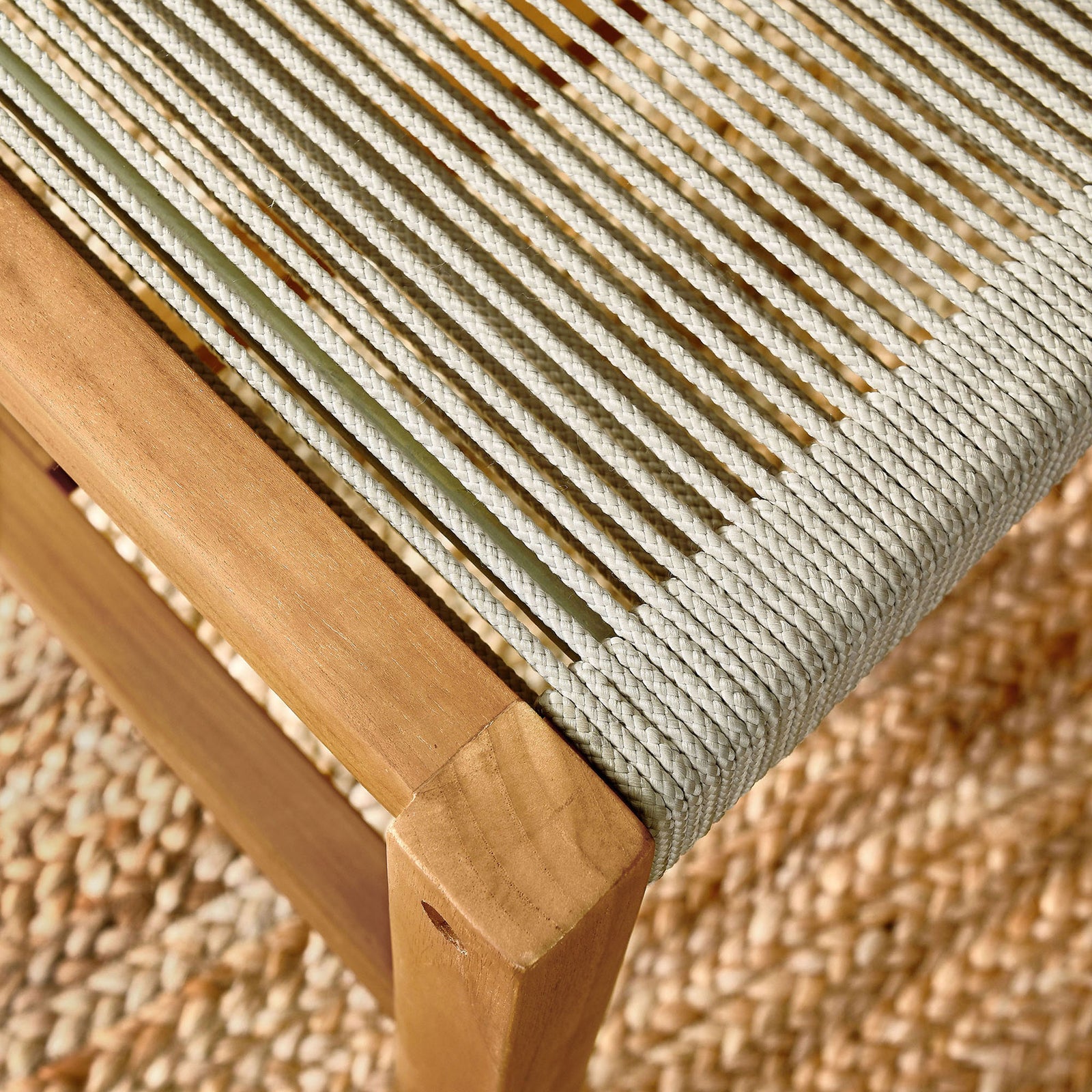 Sunlit natural rope seat and teak frame rest on a textured outdoor rug for relaxed patio dining || EEI-6805-NAT-NAT || detail_room