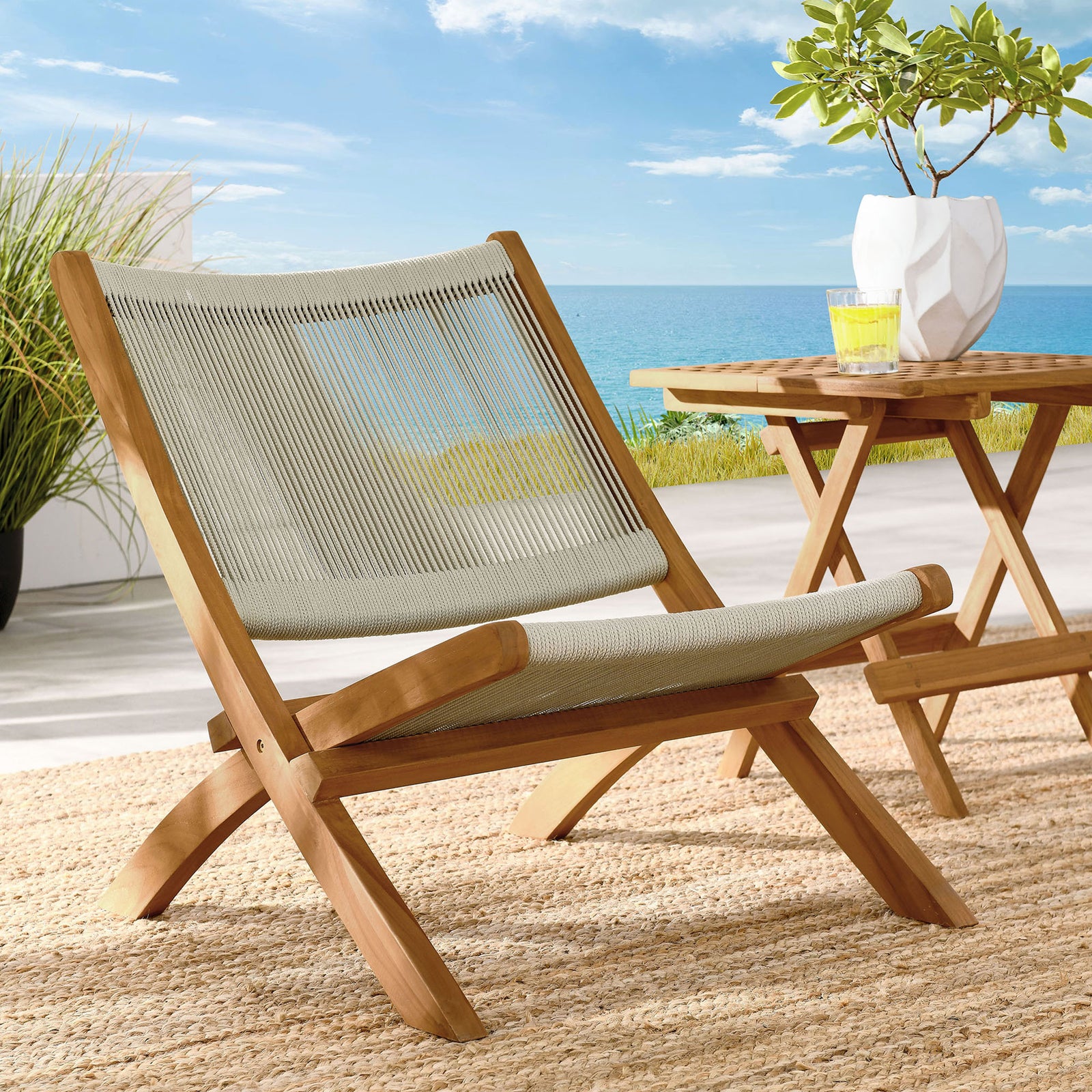 Teak and natural rope lounge chair brings relaxed style to a sunlit coastal terrace vignette || EEI-6808-NAT-NAT || front_angle_room