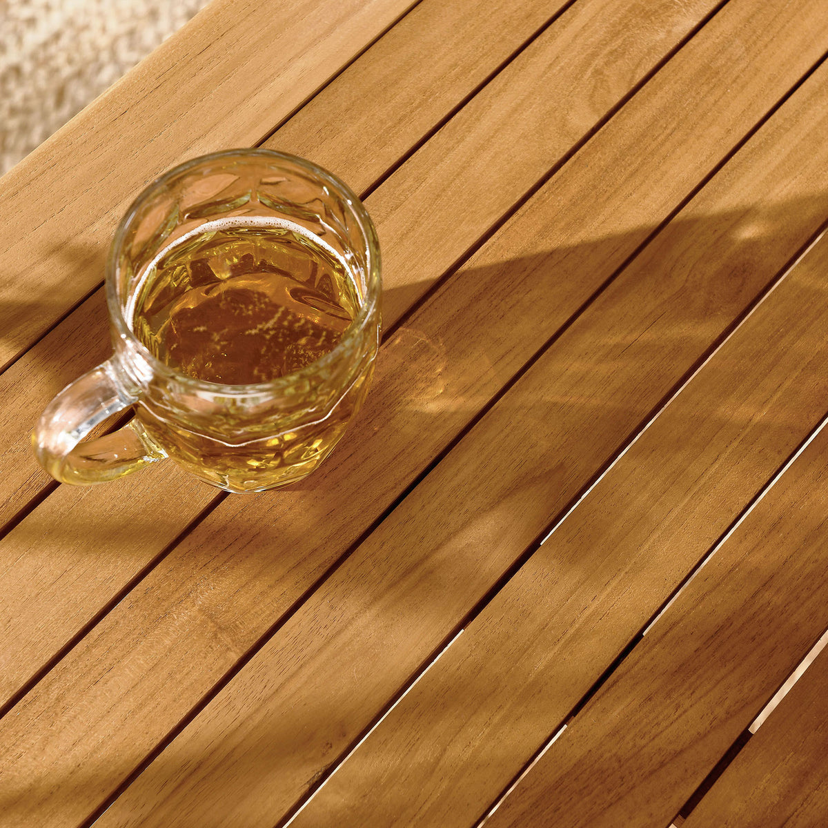 Slatted natural teak tabletop styled with beverages, adding warm inviting character to this patio dining table. || EEI-6814-NAT || detail_room