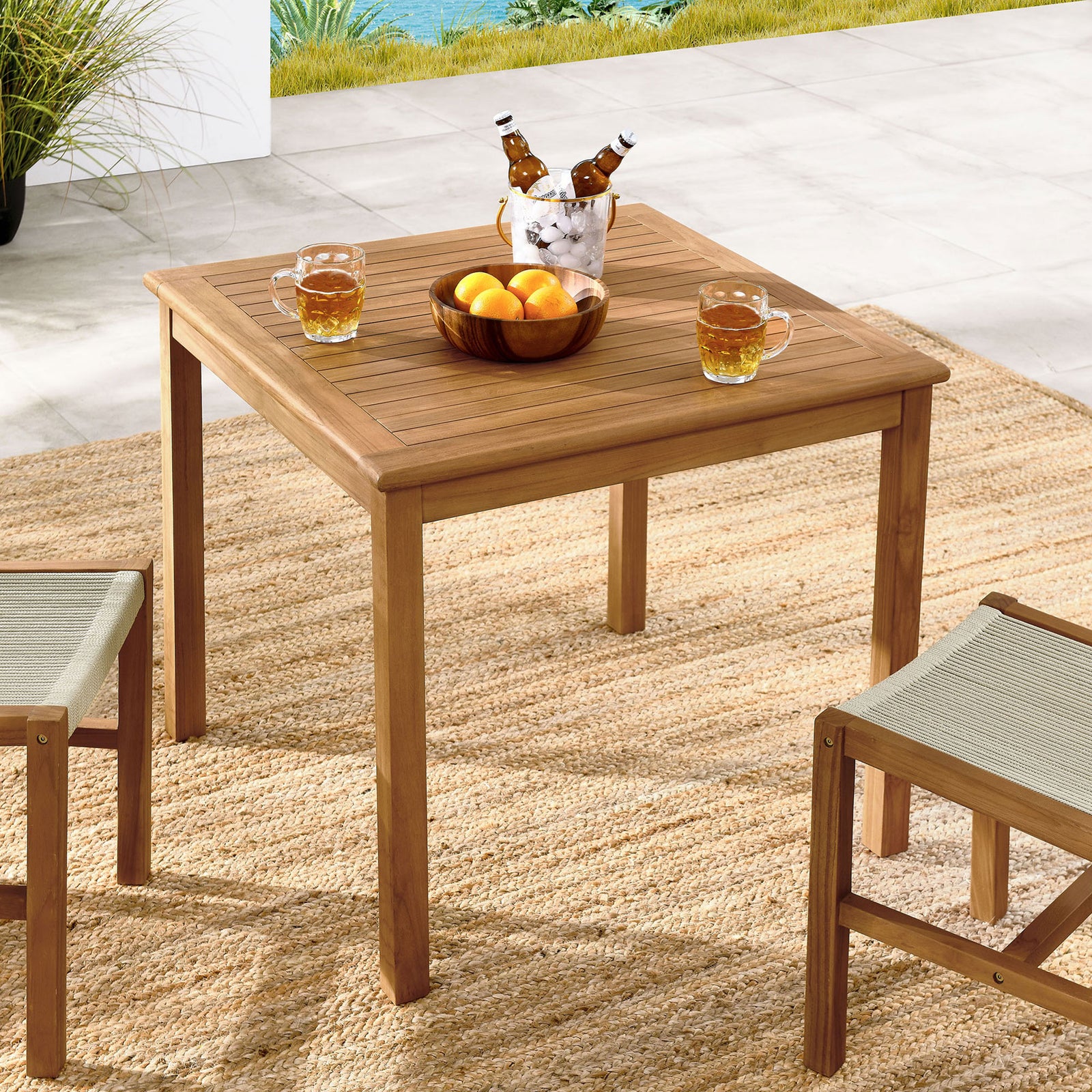 Vienna 34 inch teak patio table arranged with drinks and chairs, creating a relaxed outdoor gathering spot. || EEI-6814-NAT || front_angle_room