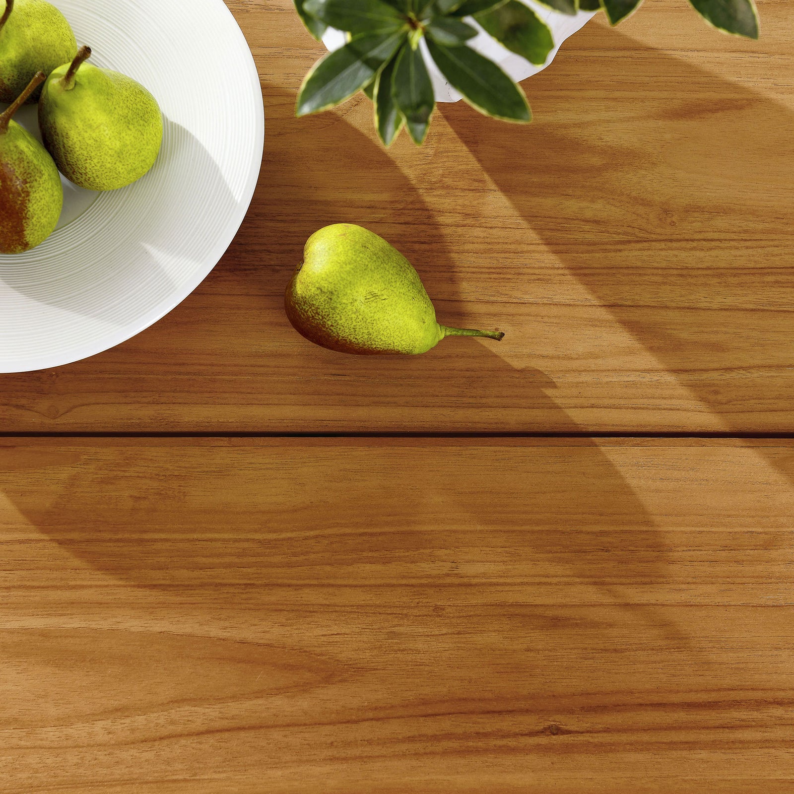 Slatted natural teak tabletop styled with fruit and greenery, creating a warm casual setting for outdoor meals. || EEI-6815-NAT || detail_room