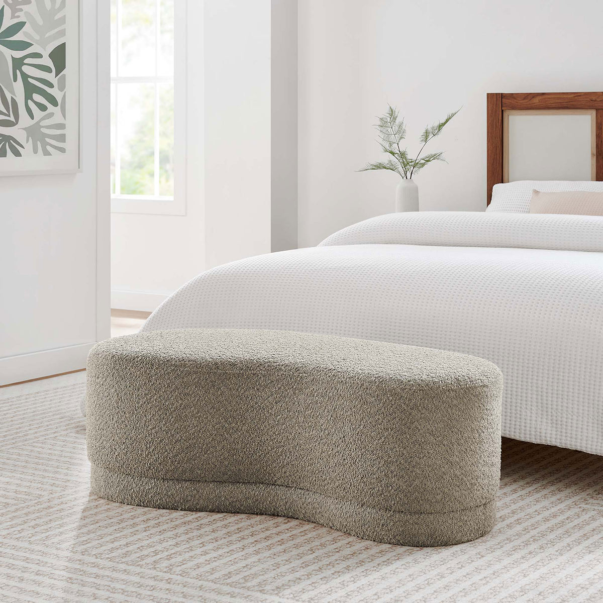 Curved Nimbus oat chenille ottoman bench placed at the foot of a bed in a serene neutral bedroom || EEI-6816-OAT || front_angle_room
