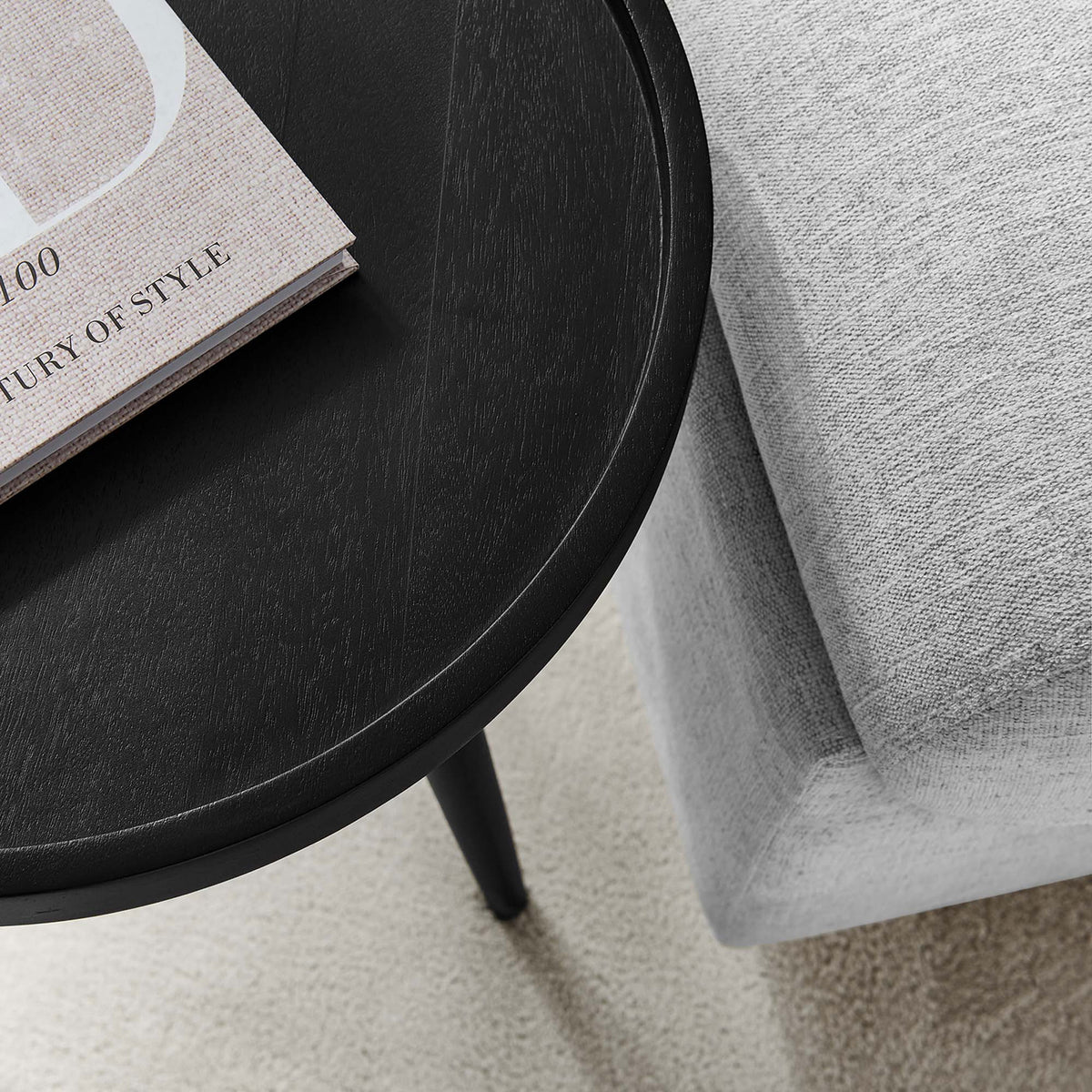 Black tray top side table beside a light sofa with a book resting on the smooth wood surface || EEI-6830-BLK || detail_room