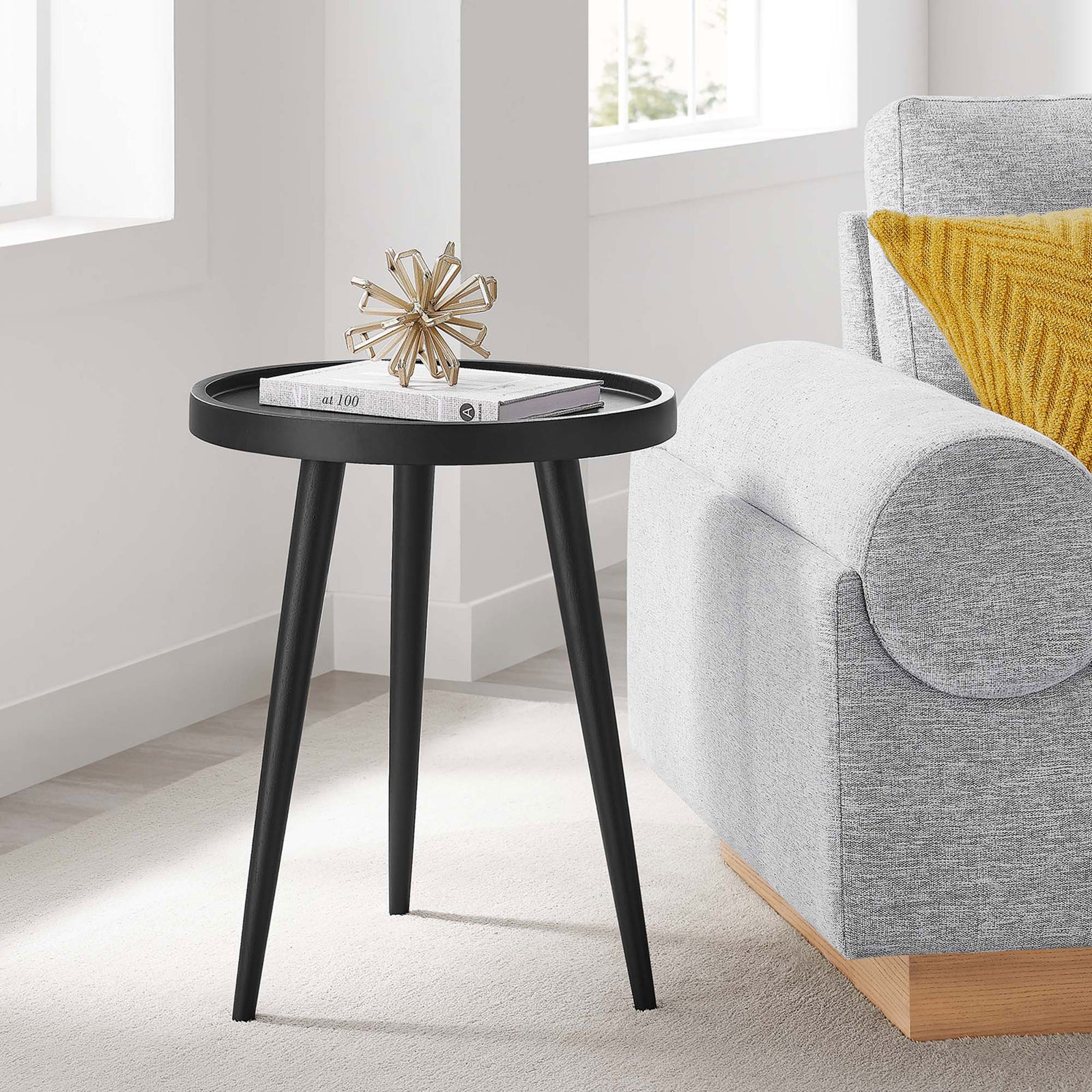 Black round side table next to a gray sofa with decor in a bright modern living room || EEI-6830-BLK || front_angle_room
