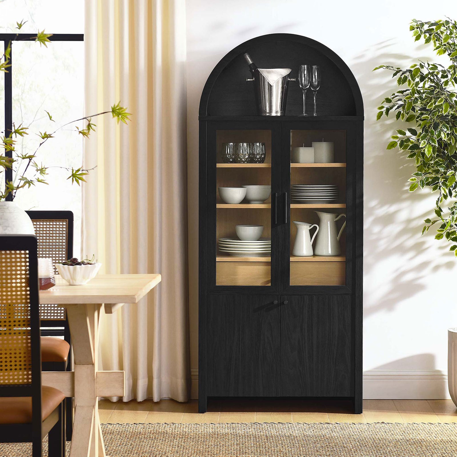 Evie arched display cabinet used as a bar cabinet, showcasing glassware in a bright dining room || EEI-6834-BLK-OAK || front_room