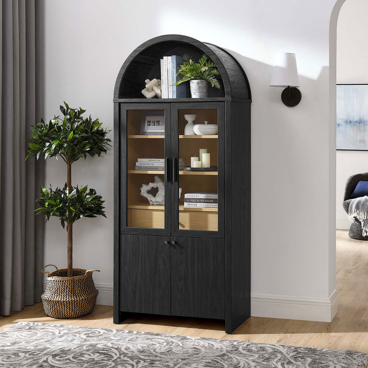 Evie arched display cabinet styled in a modern living room with books and decor on the shelves || EEI-6834-BLK-OAK || front_angle_room