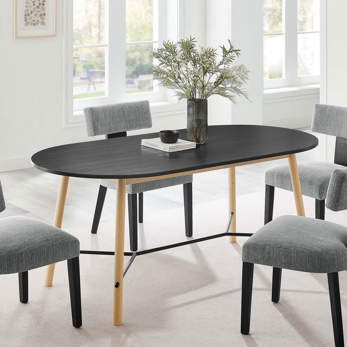 Black oval dining table styled with gray chairs and greenery, creating a welcoming modern dining space || EEI-6836-BLK-OAK || front_angle_room