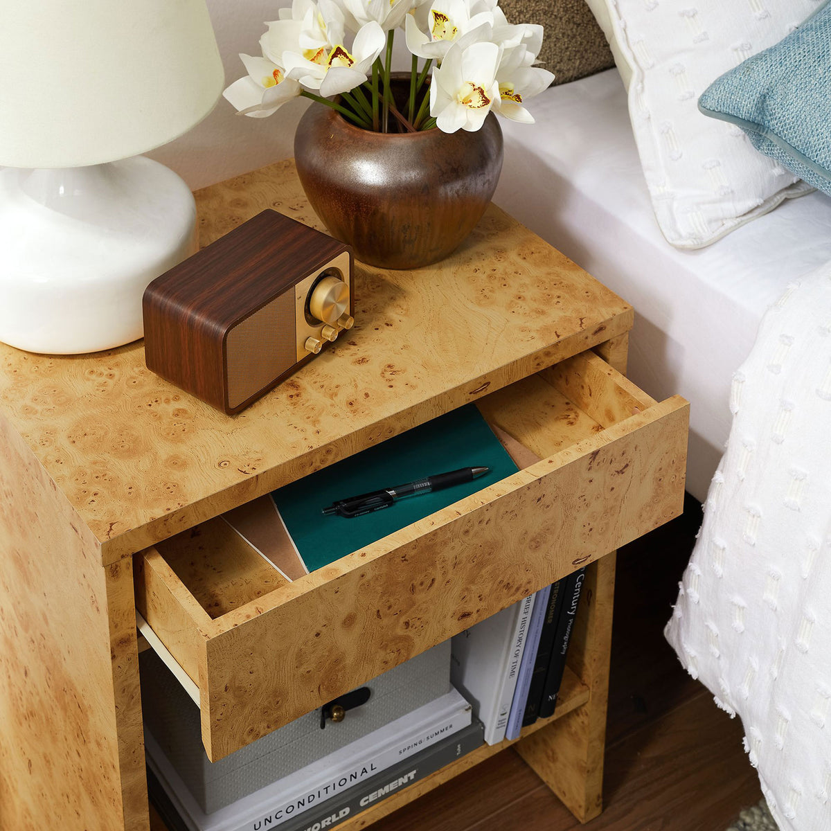 Hudson burl wood nightstand in use with drawer open and shelf neatly organized beside a contemporary upholstered bed. || EEI-6856-BUR || storage_open_room