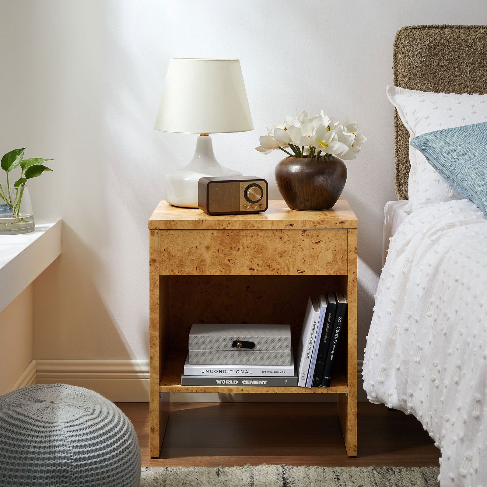 Hudson burl wood nightstand styled beside a bed, topped with decor to showcase its warm modern bedroom appeal. || EEI-6856-BUR || front_angle_room