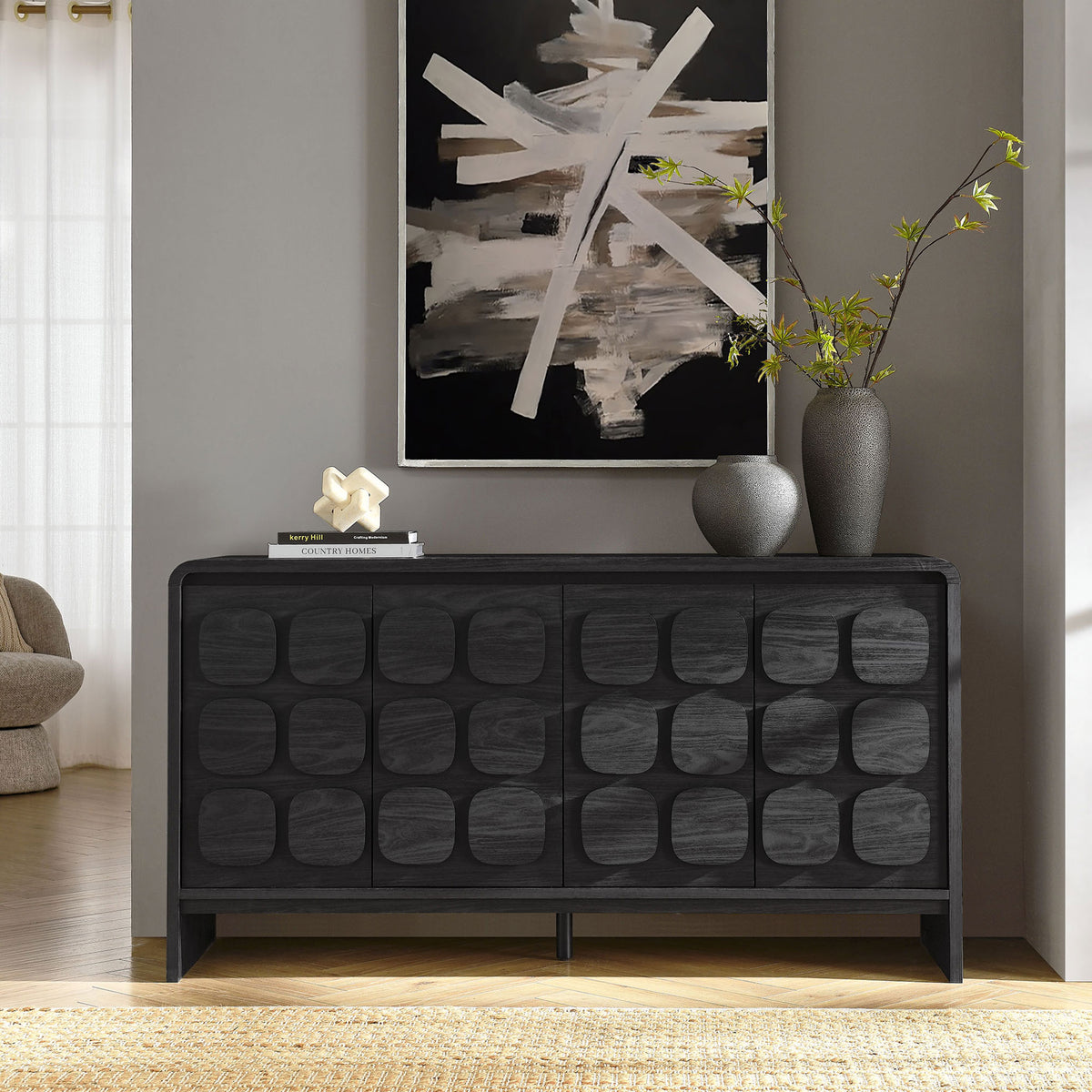 Black sideboard with sculpted doors styled in a modern living room with artwork and decorative vases || EEI-6862-BLK || front_room