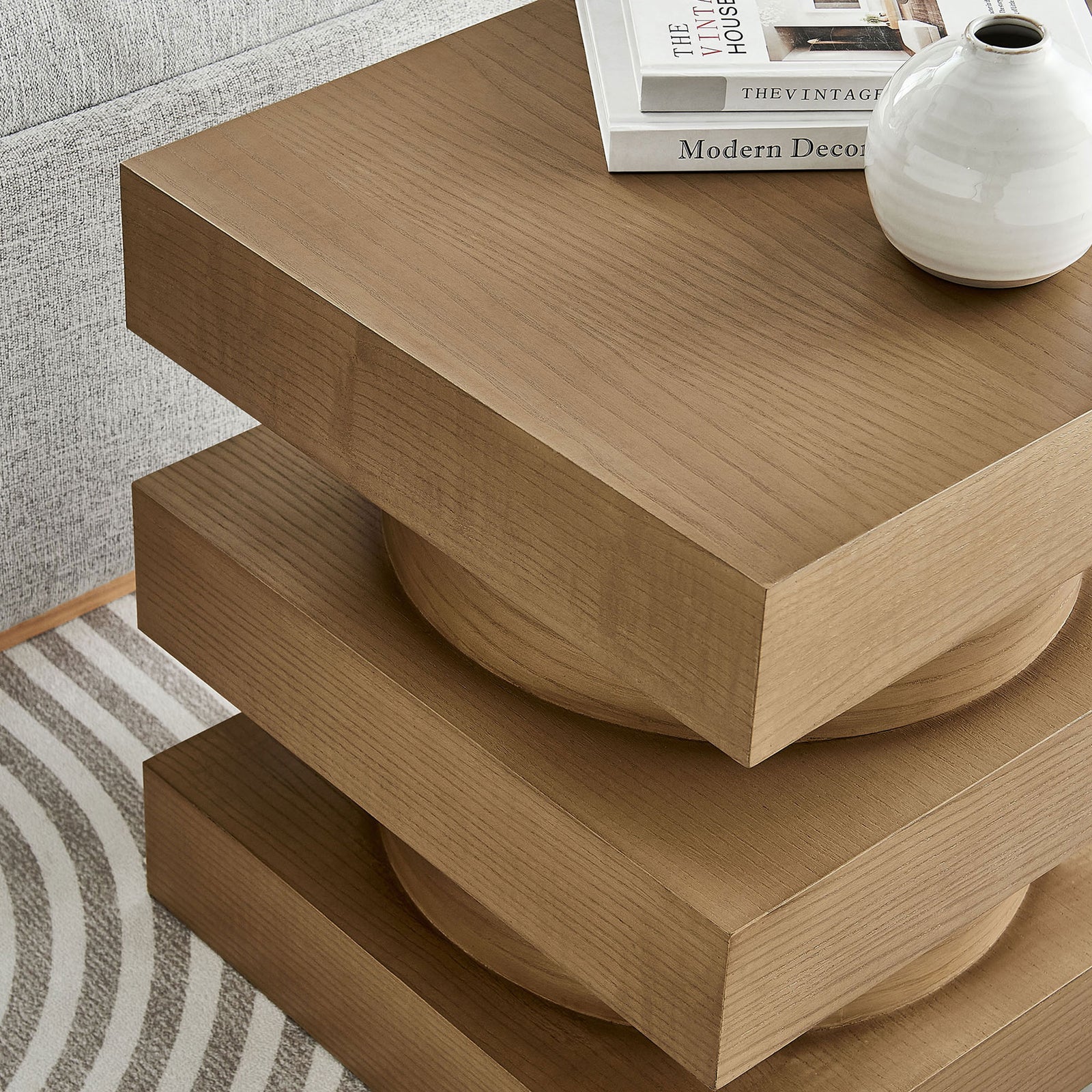 Totem end table styled with books and decor beside a sofa, adding sculptural warmth to the living room || EEI-6864-CAS || detail_room