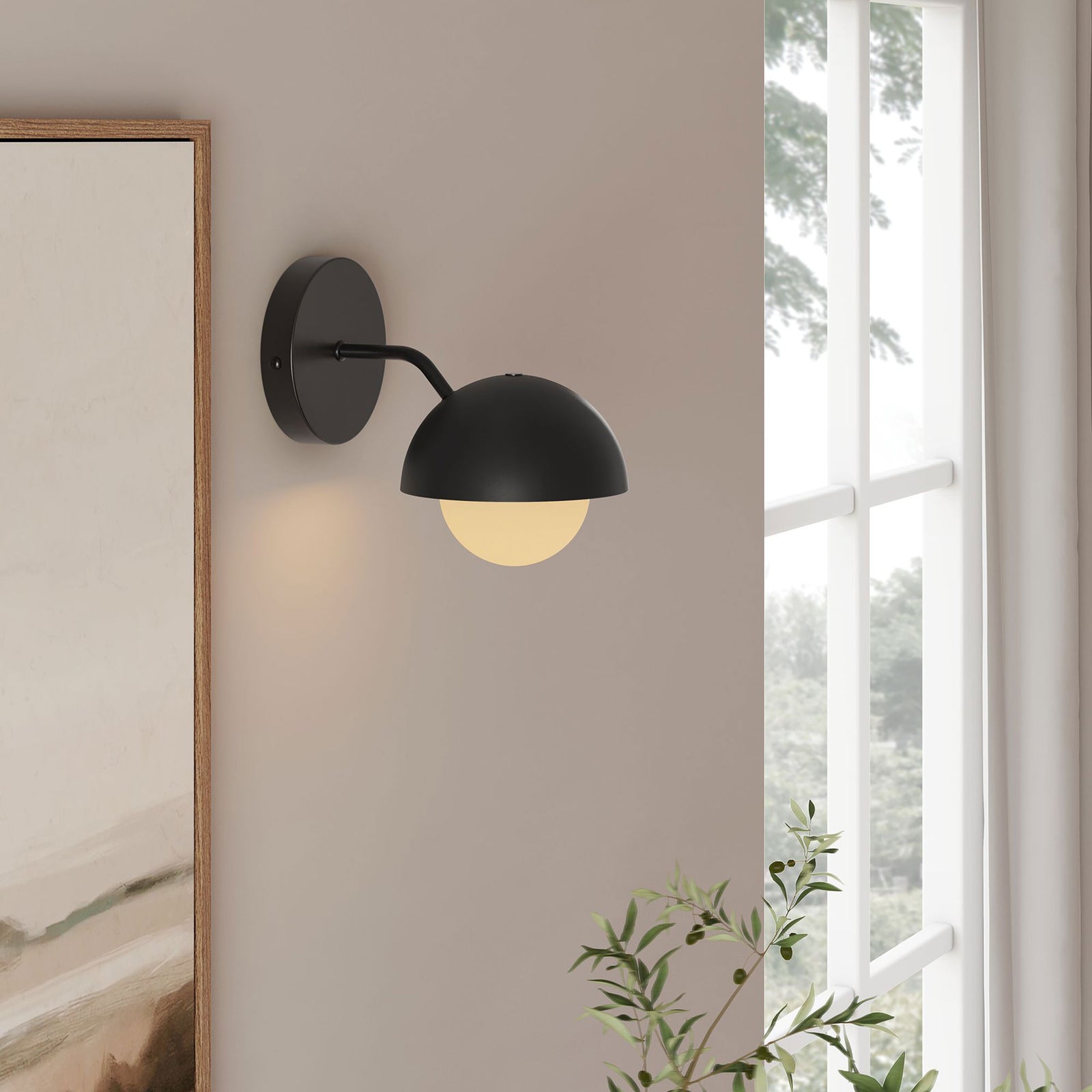 Single black globe wall sconce glows beside a bright window, illuminating the tranquil modern room || EEI-6871-BLK || front_angle_on_room