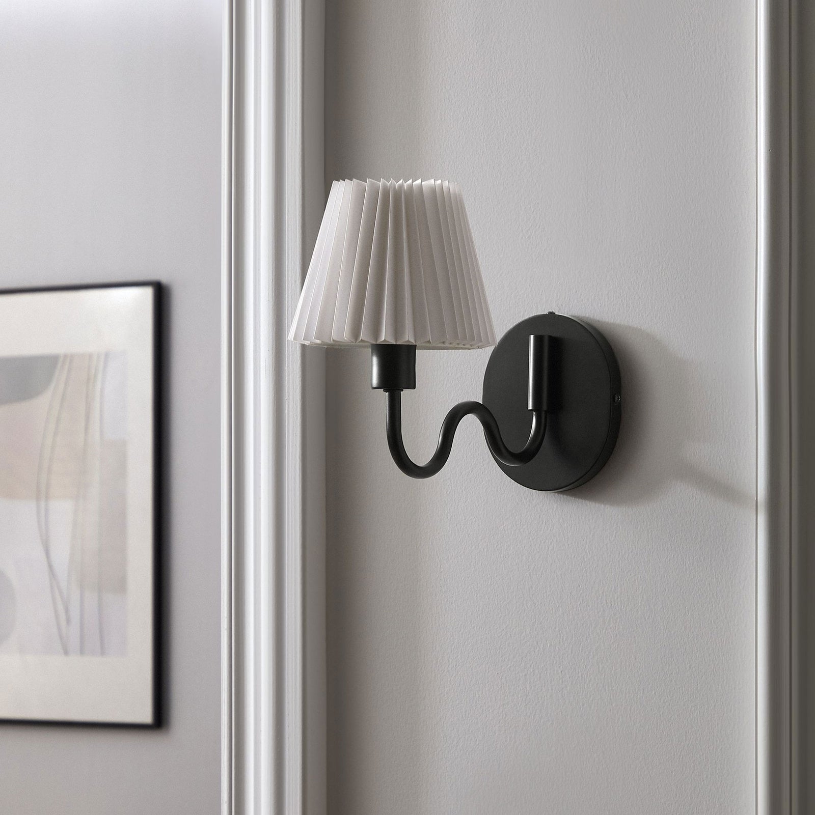 Black squiggle arm sconce with pleated shade brings modern character to a neutral hallway or entry wall. || EEI-6873-BLK || front_angle_room