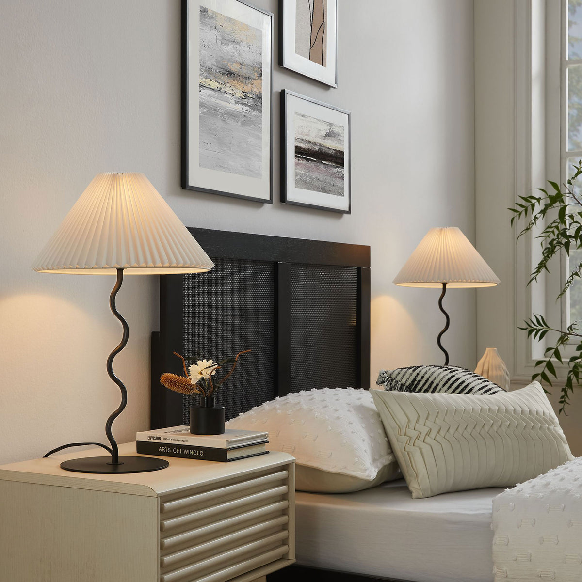 Warmly lit Wave squiggle table lamps casting soft ambient light on each side of a cozy modern bed || EEI-6876-BLK || front_angle_on_room