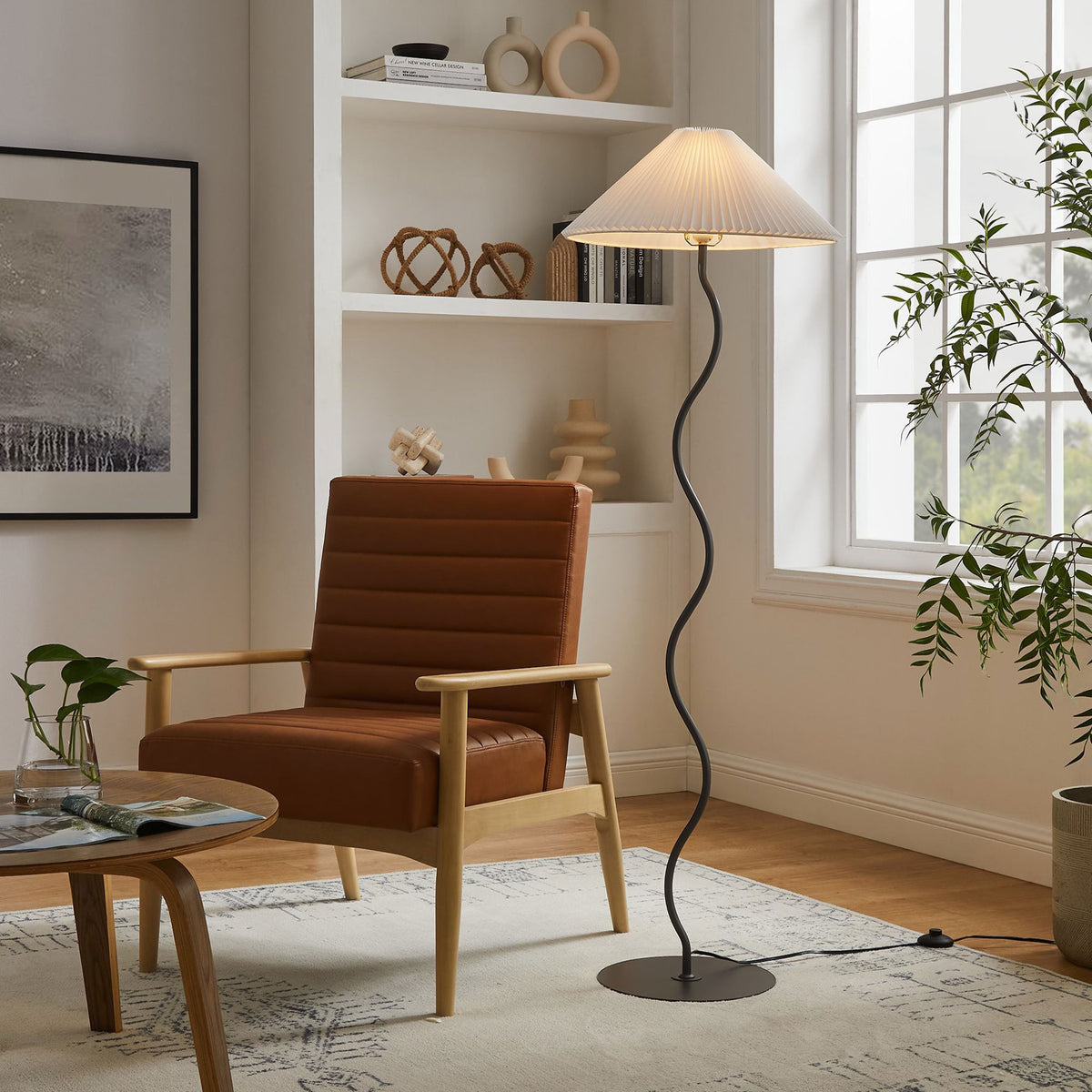 Squiggle floor lamp glowing warmly beside a cozy reading chair, creating ambient light in a stylish living room. || EEI-6877-BLK || front_on_room
