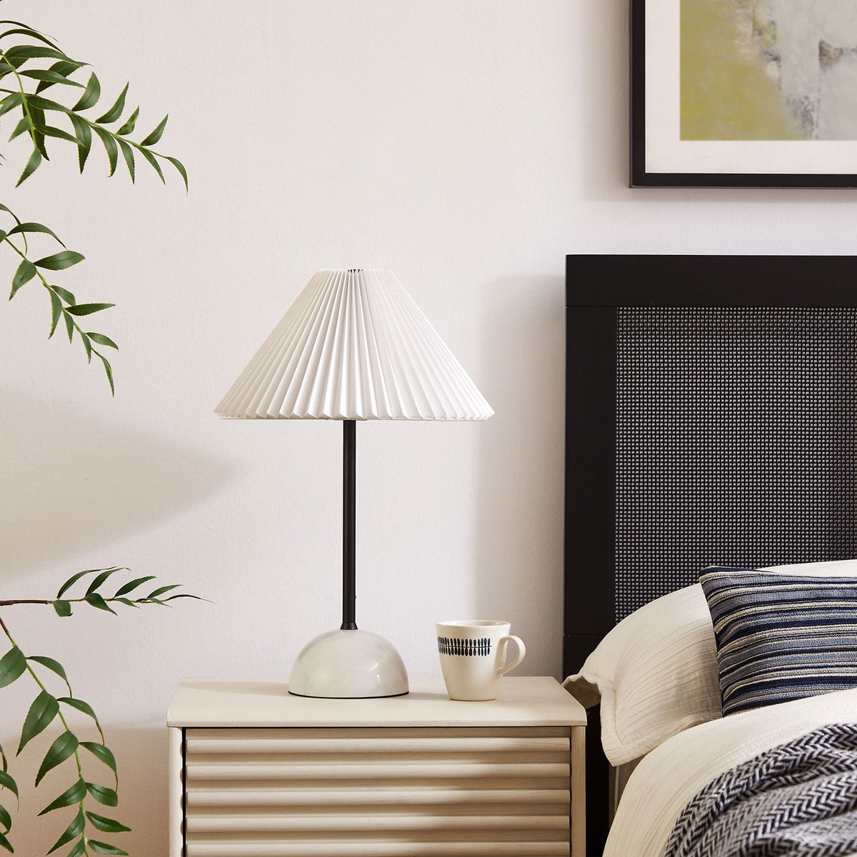 Illusion lamp styling a bedside table with its sculpted marble base and crisp pleated shade. || EEI-6878-BLK || front_angle_room