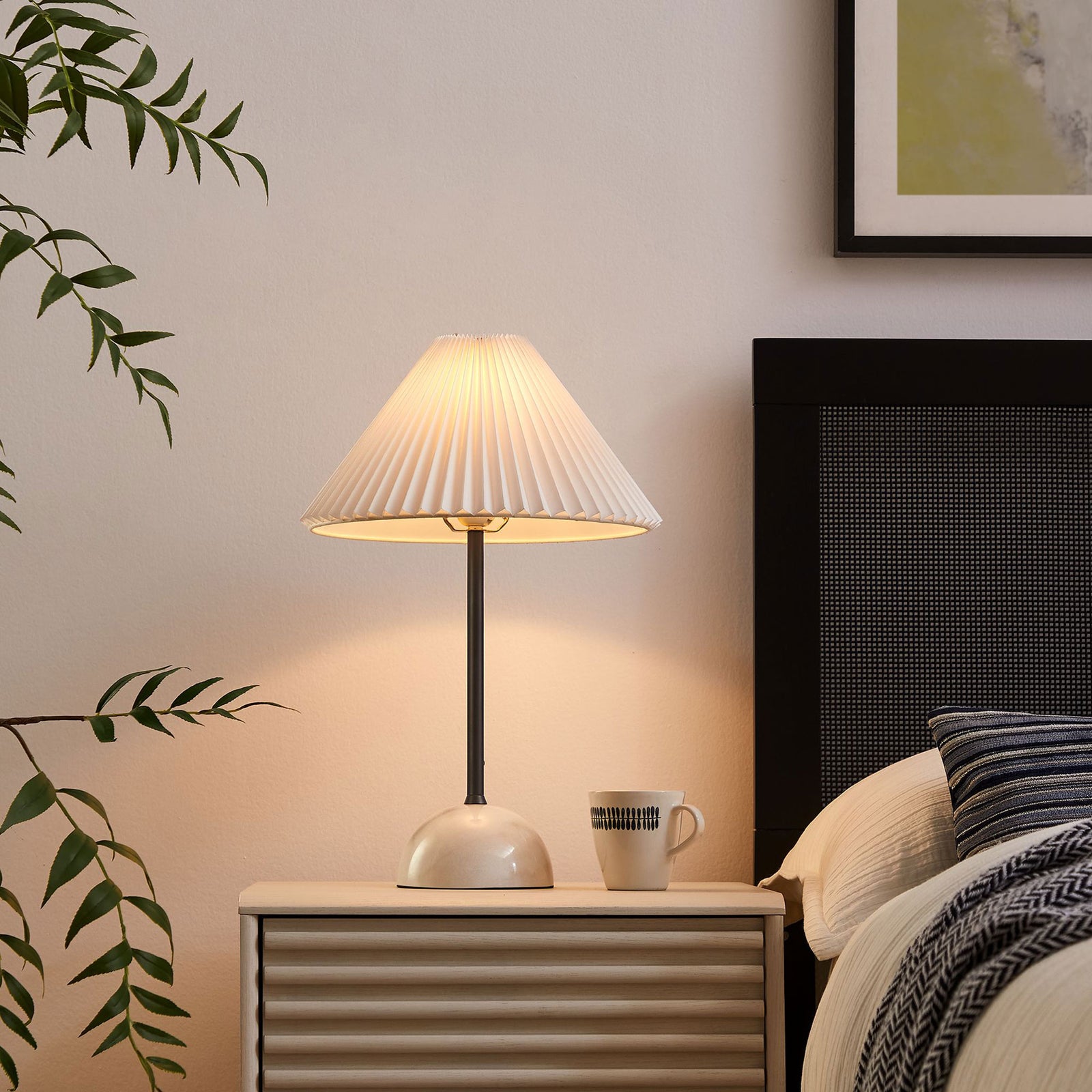 Illusion lamp casting a warm bedside glow from its pleated shade and marble dome base. || EEI-6878-BLK || front_angle_on_room