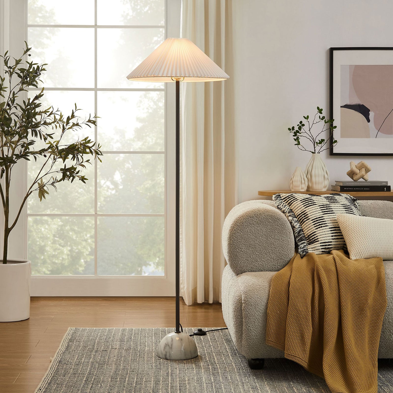 Illusion floor lamp illuminating a cozy living room beside a sofa with its pleated shade and marble dome base || EEI-6879-BLK || front_on_room