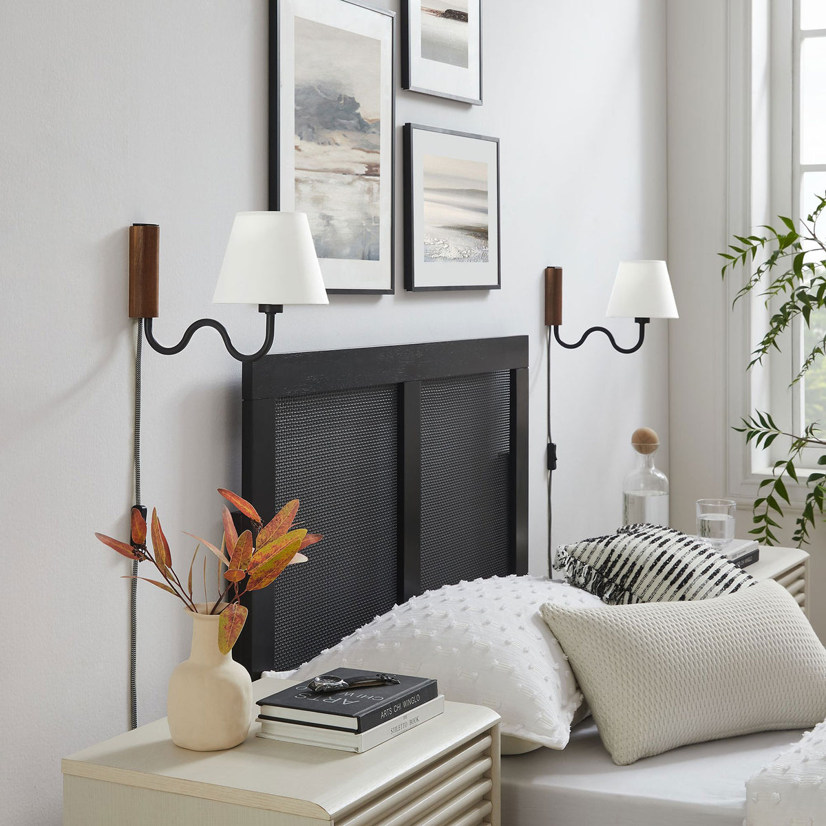 Pair of walnut and black squiggle wall sconces frame a modern headboard in a bright bedroom || EEI-6881-WAL-BLK || front_angle_room