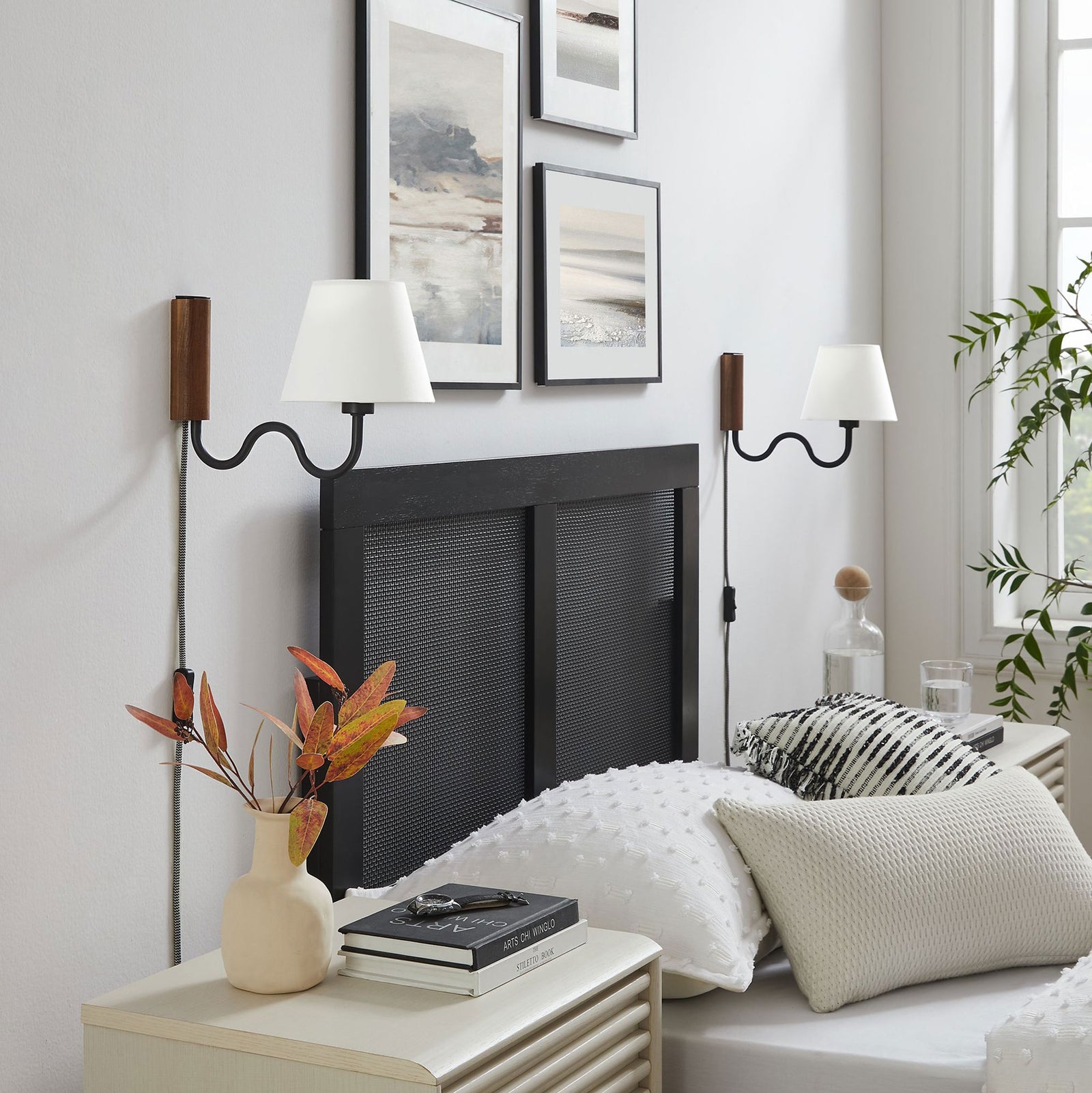 Pair of walnut and black squiggle wall sconces frame a modern headboard in a bright bedroom || EEI-6881-WAL-BLK || front_angle_room