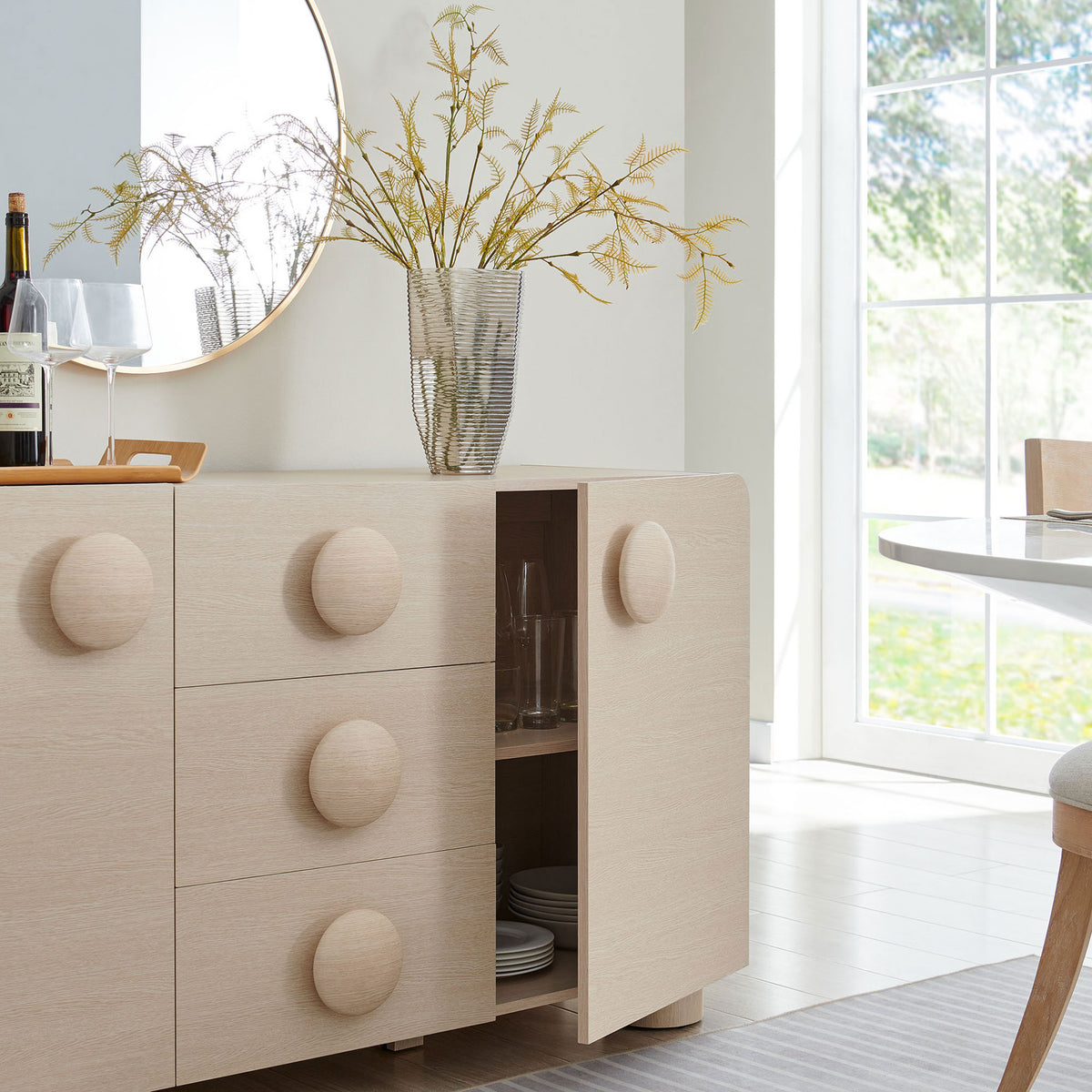 Sonnet ash sideboard styled in a bright dining room with cabinet storage open for serveware and glassware. || EEI-6892-ASH || front_angle_open_room
