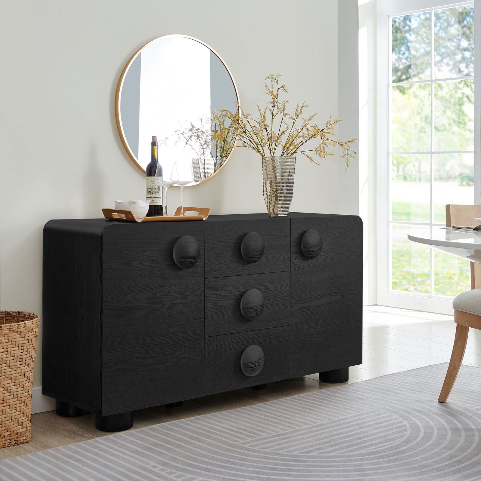 Black Sonnet sideboard styled with mirror, vase, and tray, adding sculptural storage to a contemporary dining room || EEI-6892-BLK || front_angle_room