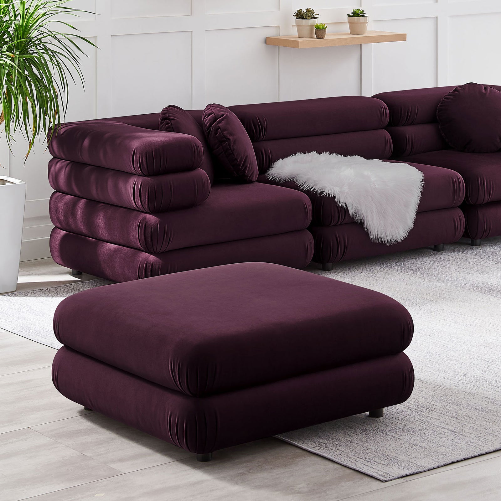 Mulberry velvet ottoman styled with the Jubilee modular seating, adding plush texture to a modern living room || EEI-6899-MUL || front_angle_room