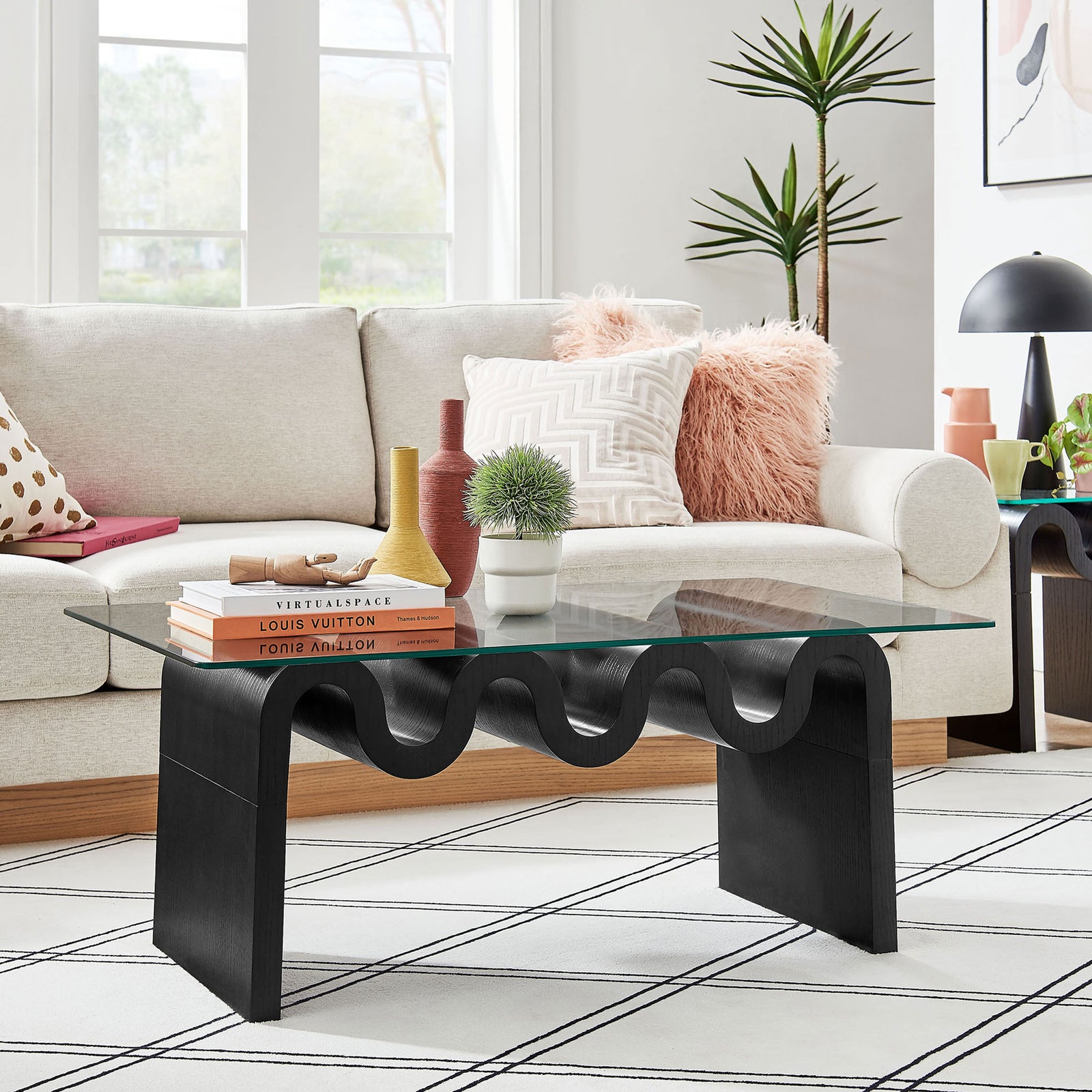 Modern statement coffee table anchors the room with its wavy base and clear glass top. || EEI-6900-BLK || front_angle_room