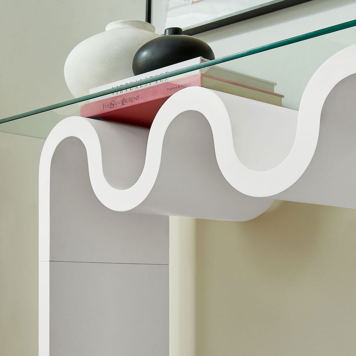Books and decor rest on the clear top, revealing the sculpted wave base. || EEI-6901-WHI || detail_room
