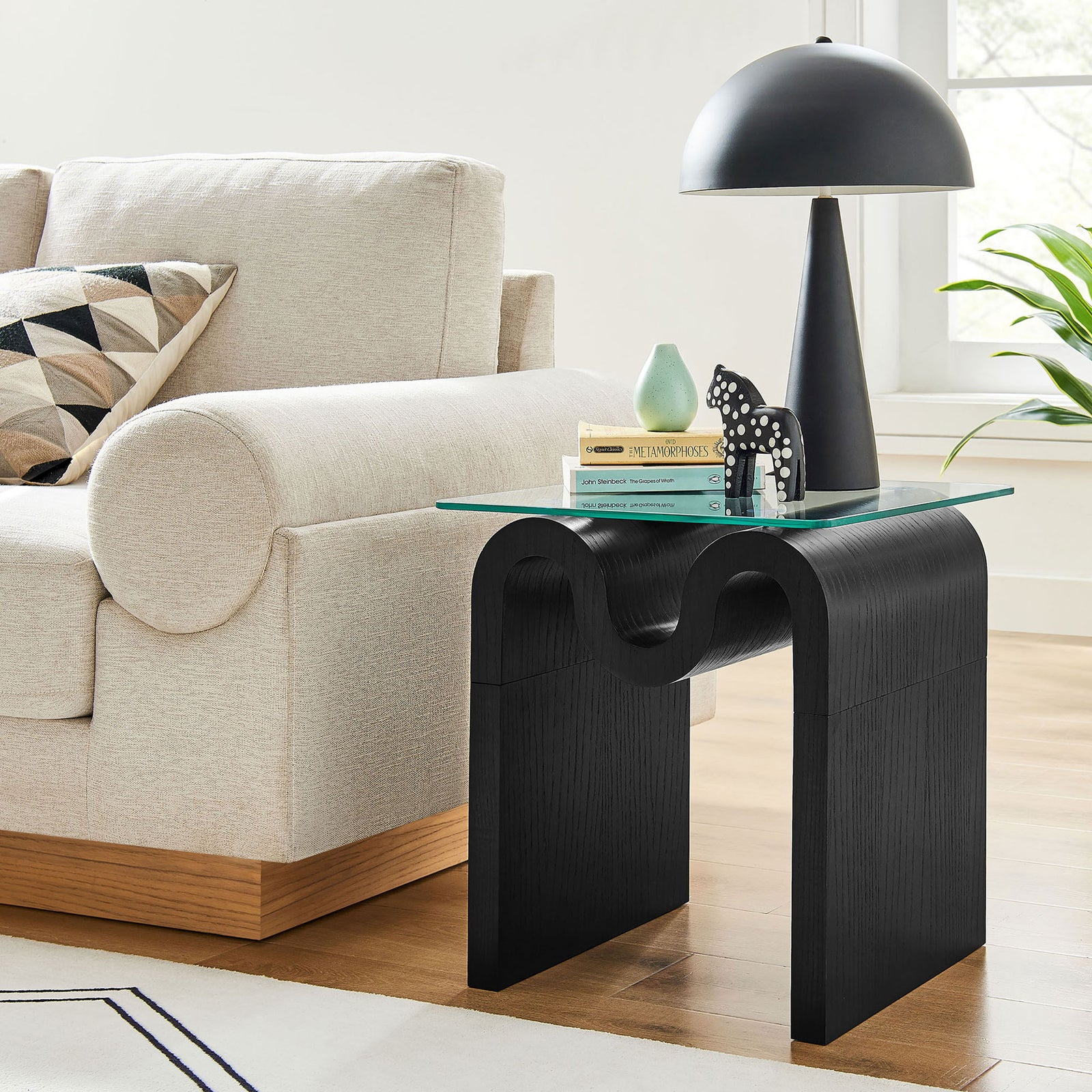 Ondine glass top side table bringing sculptural black curves and a sleek resting spot for decor to a bright living room || EEI-6902-BLK || front_angle_room