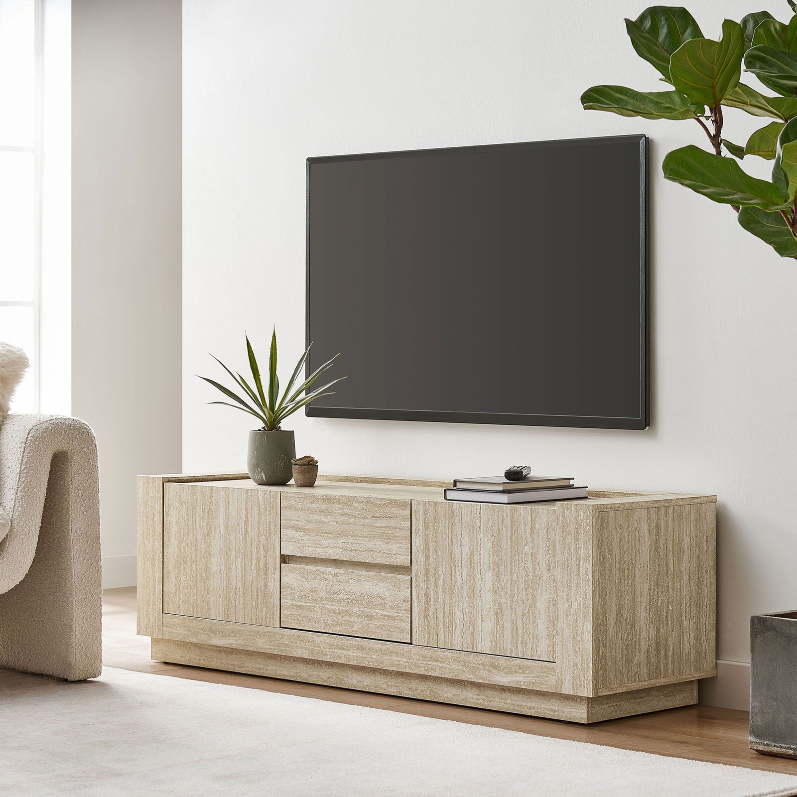 Travertine TV stand anchoring a bright living room beneath a wall mounted TV with plants and decor || EEI-6907-TRA || front_room