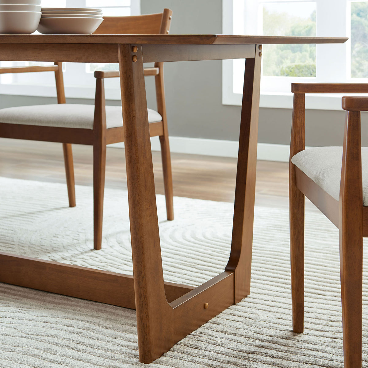 Solara walnut dining table base with matching chairs in a bright dining room on a textured rug || EEI-6914-WAL || leg_room