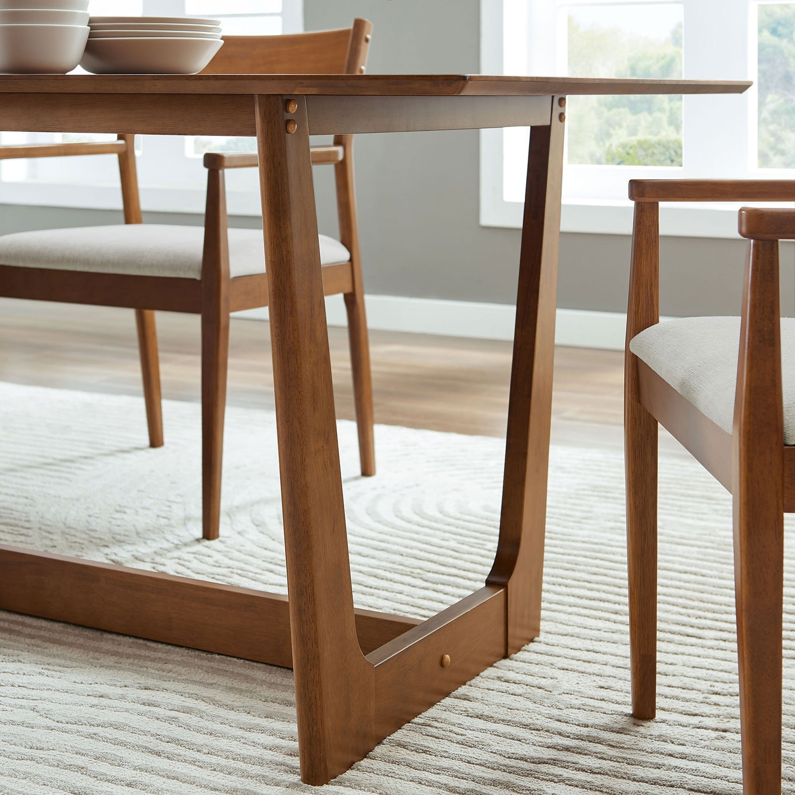 Solara walnut dining table base with matching chairs in a bright dining room on a textured rug || EEI-6914-WAL || leg_room
