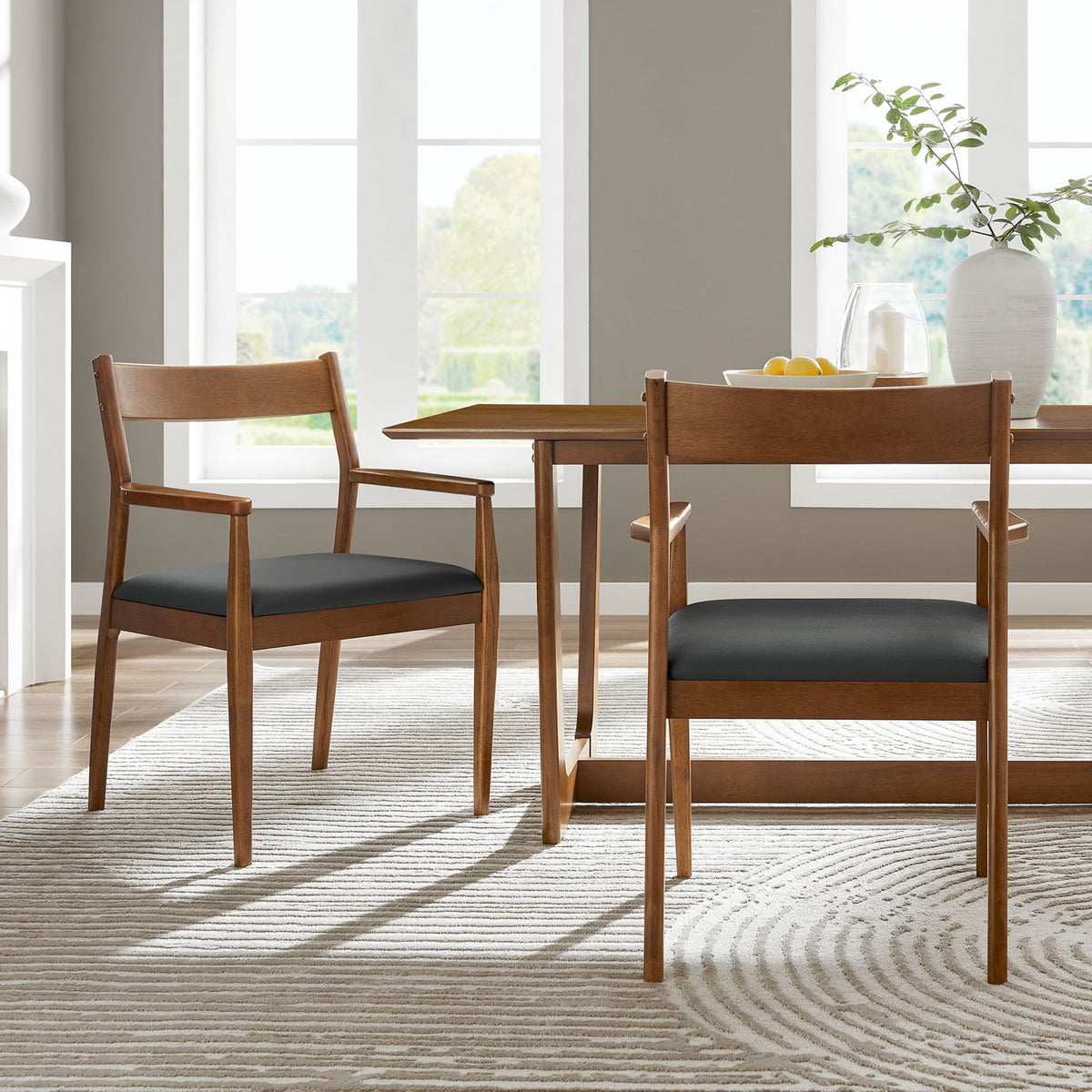 Pair of walnut dining armchairs around a table in a bright, contemporary dining room. || EEI-6915-WAL-BLK || front_angle_multi_room