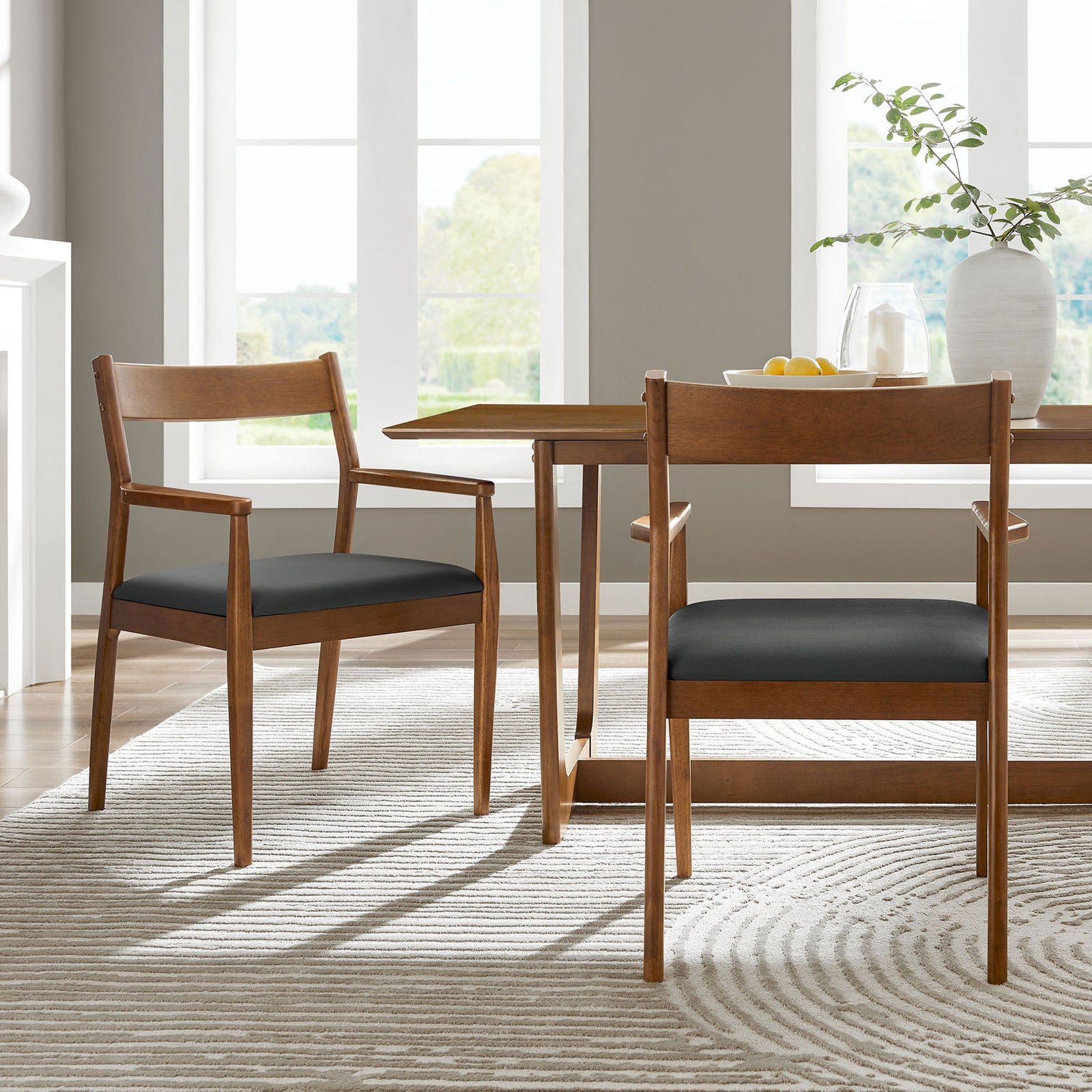 Pair of walnut dining armchairs around a table in a bright, contemporary dining room. || EEI-6915-WAL-BLK || front_angle_multi_room