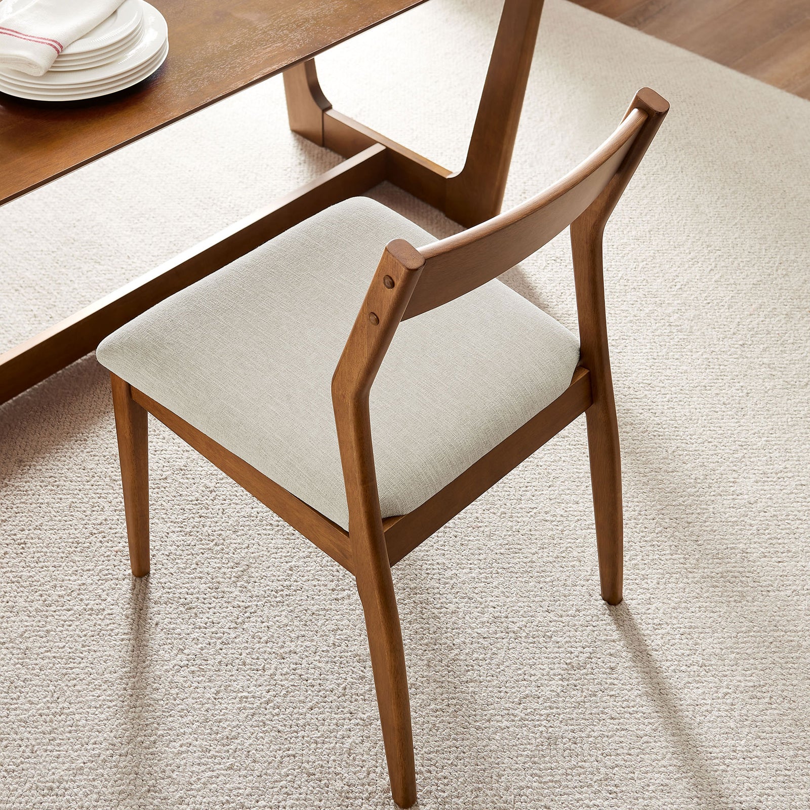 Dining chair in warm walnut finish paired with light beige cushion in a cozy modern setting || EEI-6918-WAL-HEB || top_angle_room