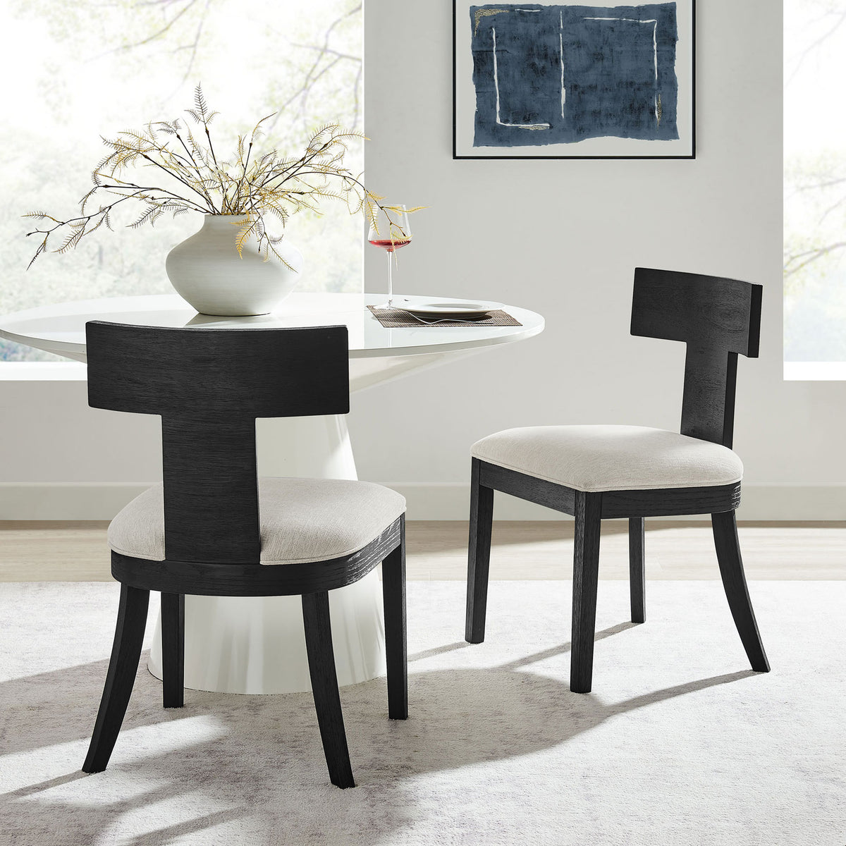 Set of two black wood dining chairs with ivory seats styled around a modern pedestal dining table || EEI-6923-BLK-HEI || front_angle_multi_room