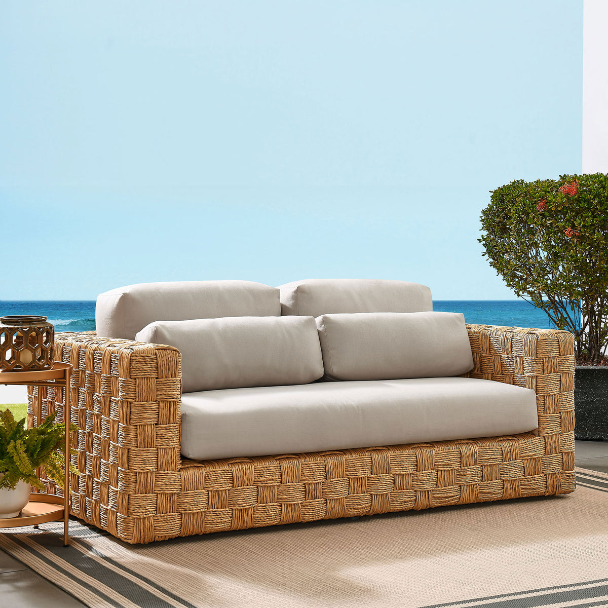 Thames wicker loveseat creates a serene patio retreat with deep cushions and inviting neutral tones. || EEI-6924-NAT-LGR || front_angle_room