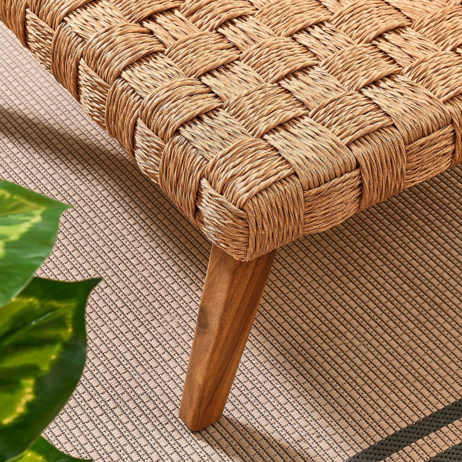 Corner of the coffee table styled on an outdoor rug with greenery accenting the warm wood and rattan tones || EEI-6926-NAT || leg_room