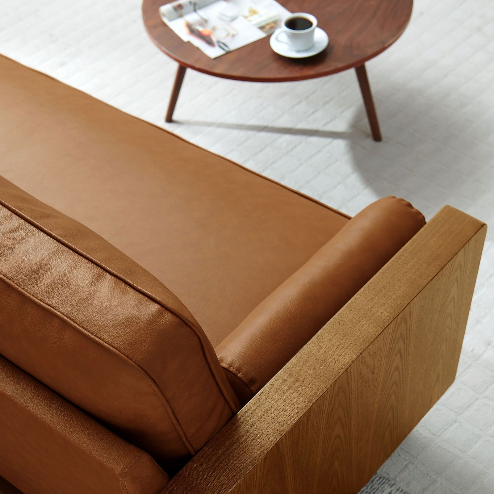 Cozy walnut tan vegan leather sofa detail with bolster cushion beside a mid-century round coffee table || EEI-6942-WAL-TAN || detail_room