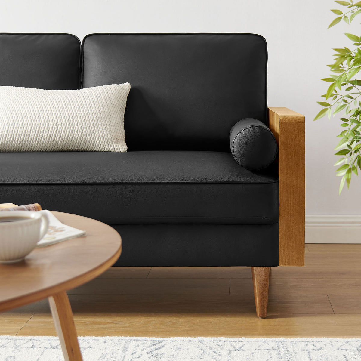 Kellan loveseat styled in a cozy living room with accent pillow, warm wood floor, and leafy greenery || EEI-6943-WAL-BLK || detail_room