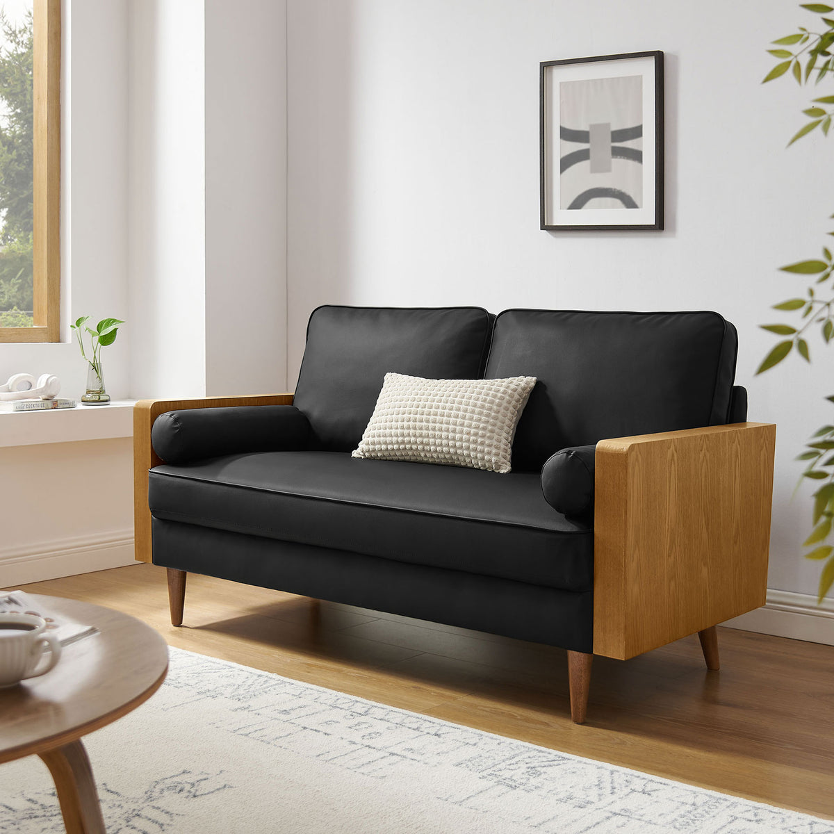 Black vegan leather Kellan loveseat with walnut wood arms anchoring a bright, modern living room || EEI-6943-WAL-BLK || front_angle_room