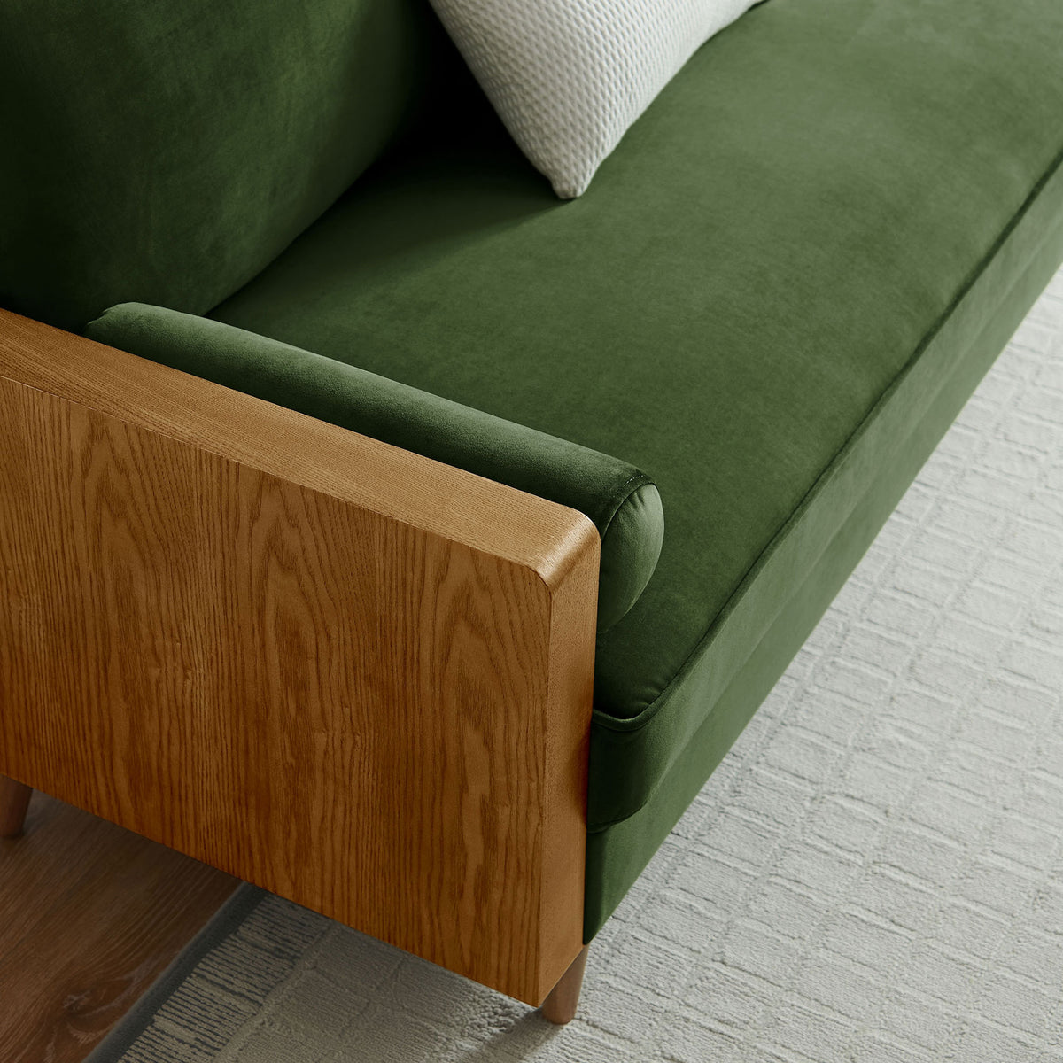 Green velvet sofa corner styled with a textured accent pillow and light rug in a bright living room || EEI-6944-WAL-MOG || detail_room